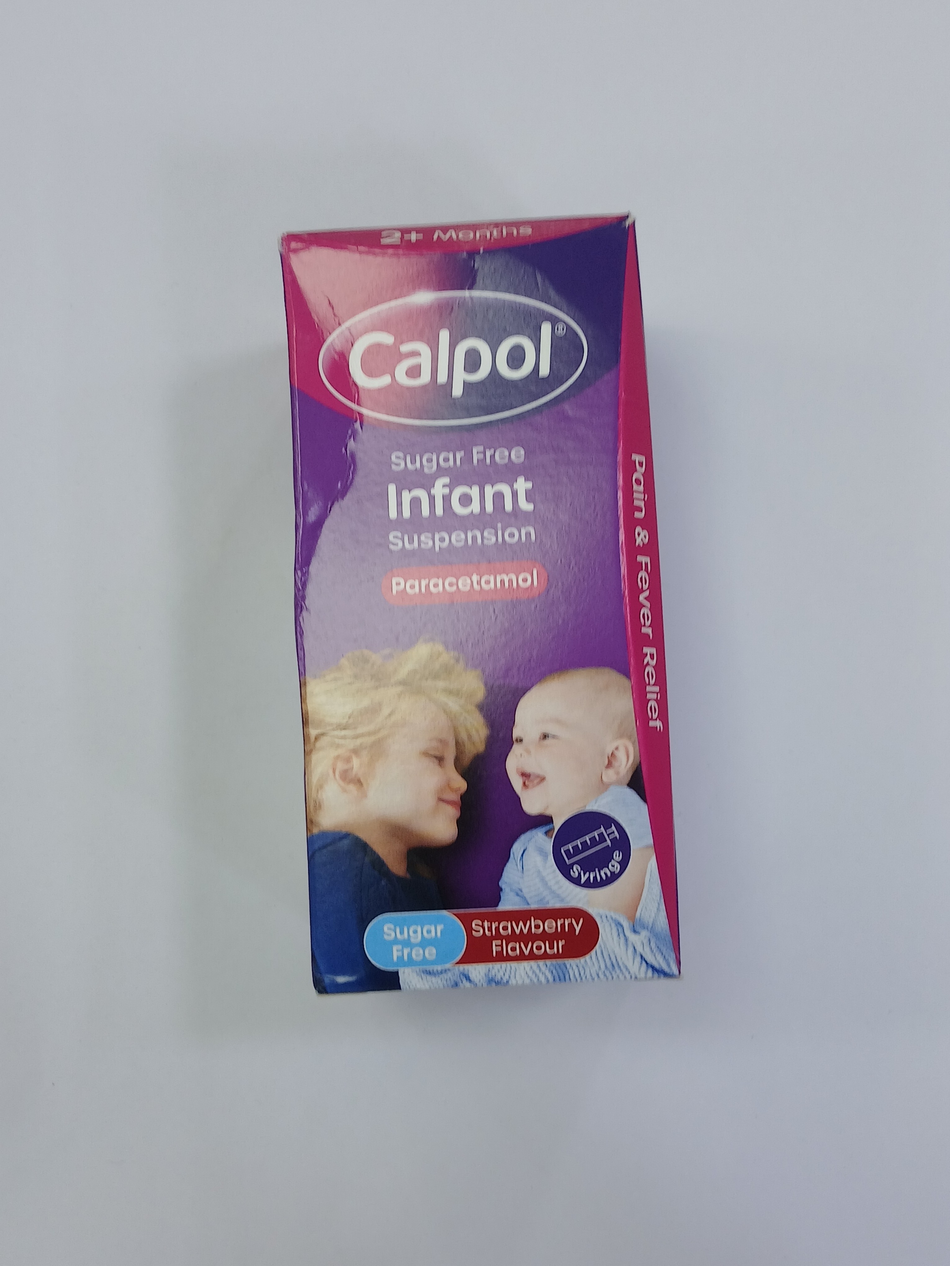A purple and white cardboard box packaging displays a strawberry-flavored infant suspension label with images of a smiling baby and a child, alongside text indicating it is sugar-free and contains paracetamol.