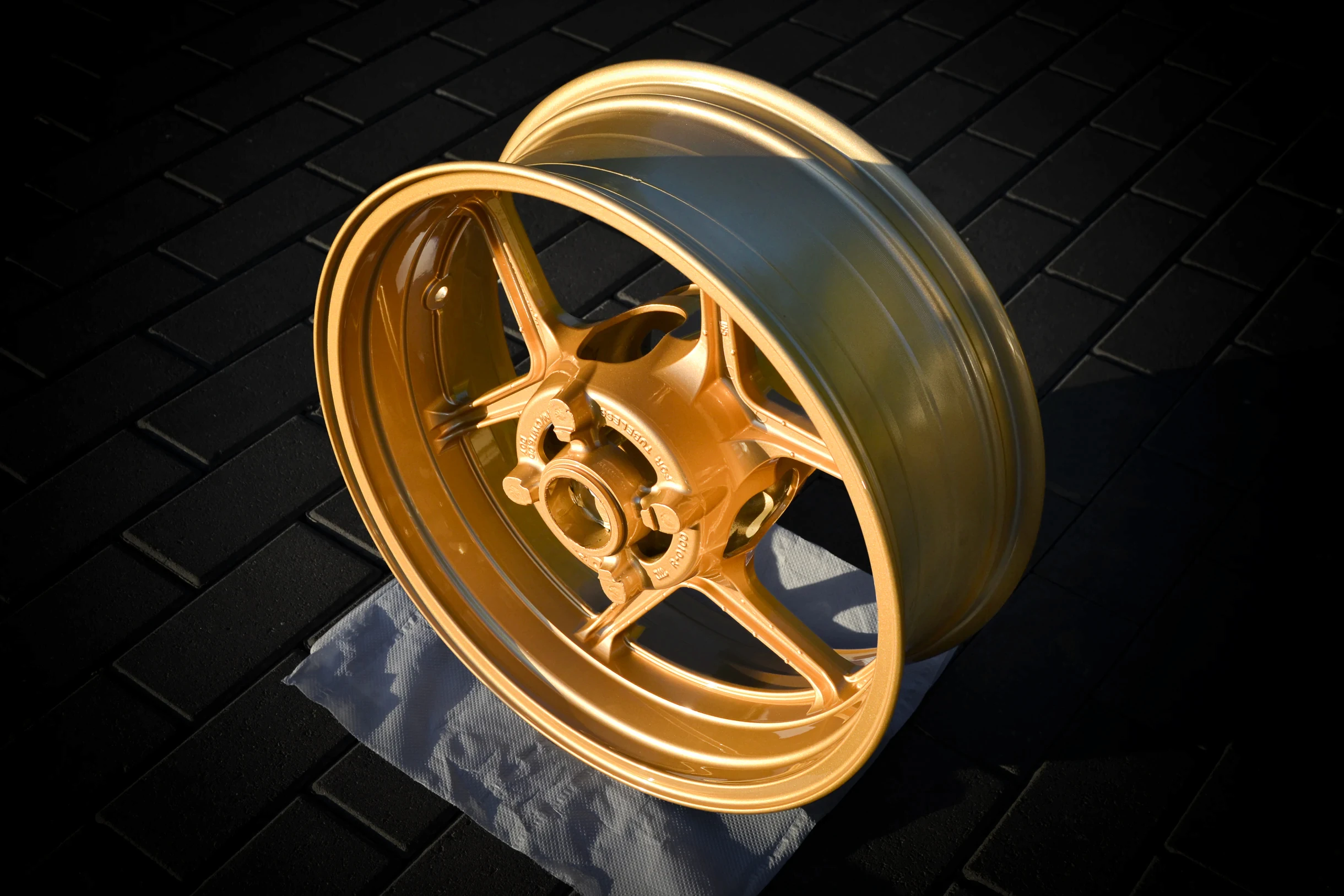Goldfarbene Motorradfelge mit glänzender Oberfläche, Gesamtansicht bei AT Plus.