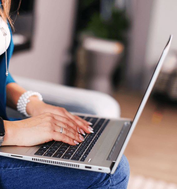 Close-up of a female website designer typing on a laptop, working on a Shopify website design project in a calm home office setting