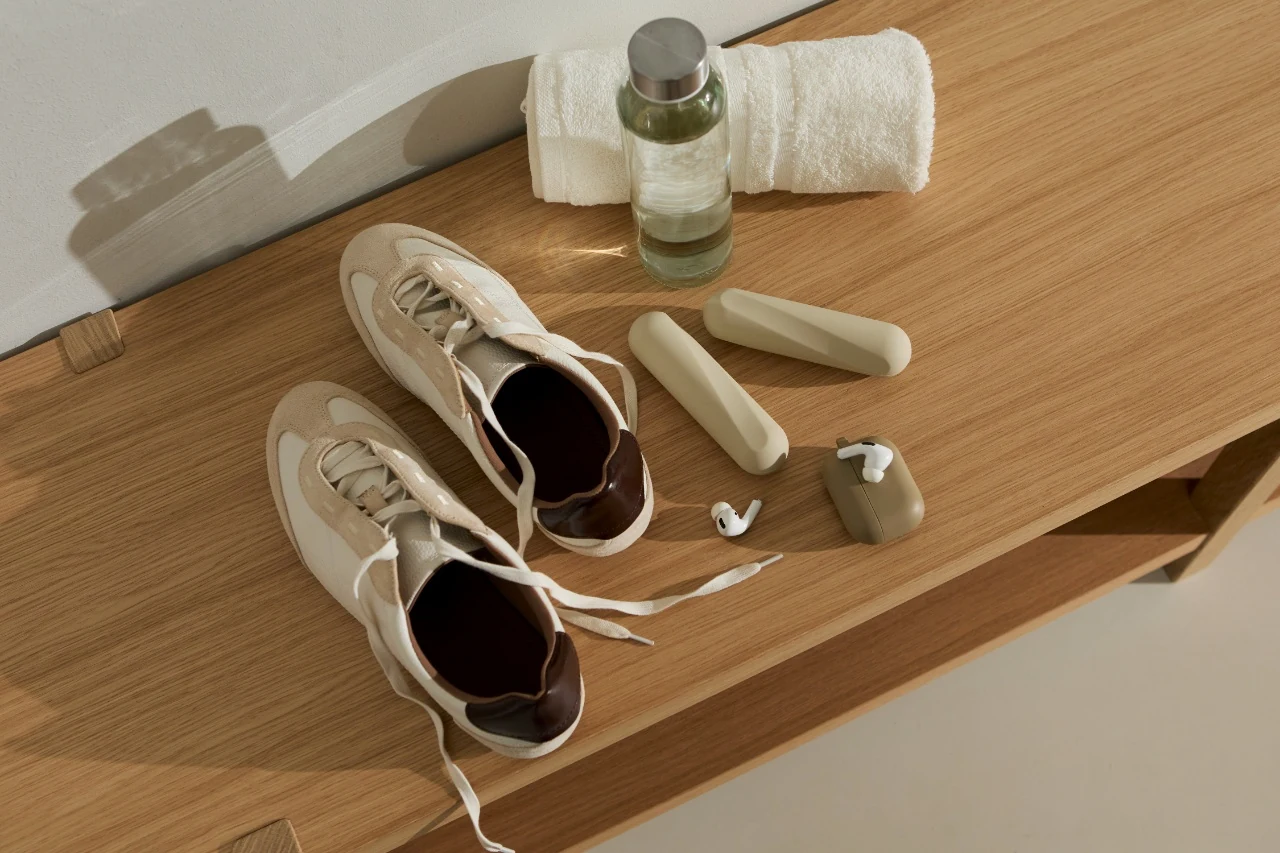 Trainers, a towel and a water bottle laid out on a wooden bench