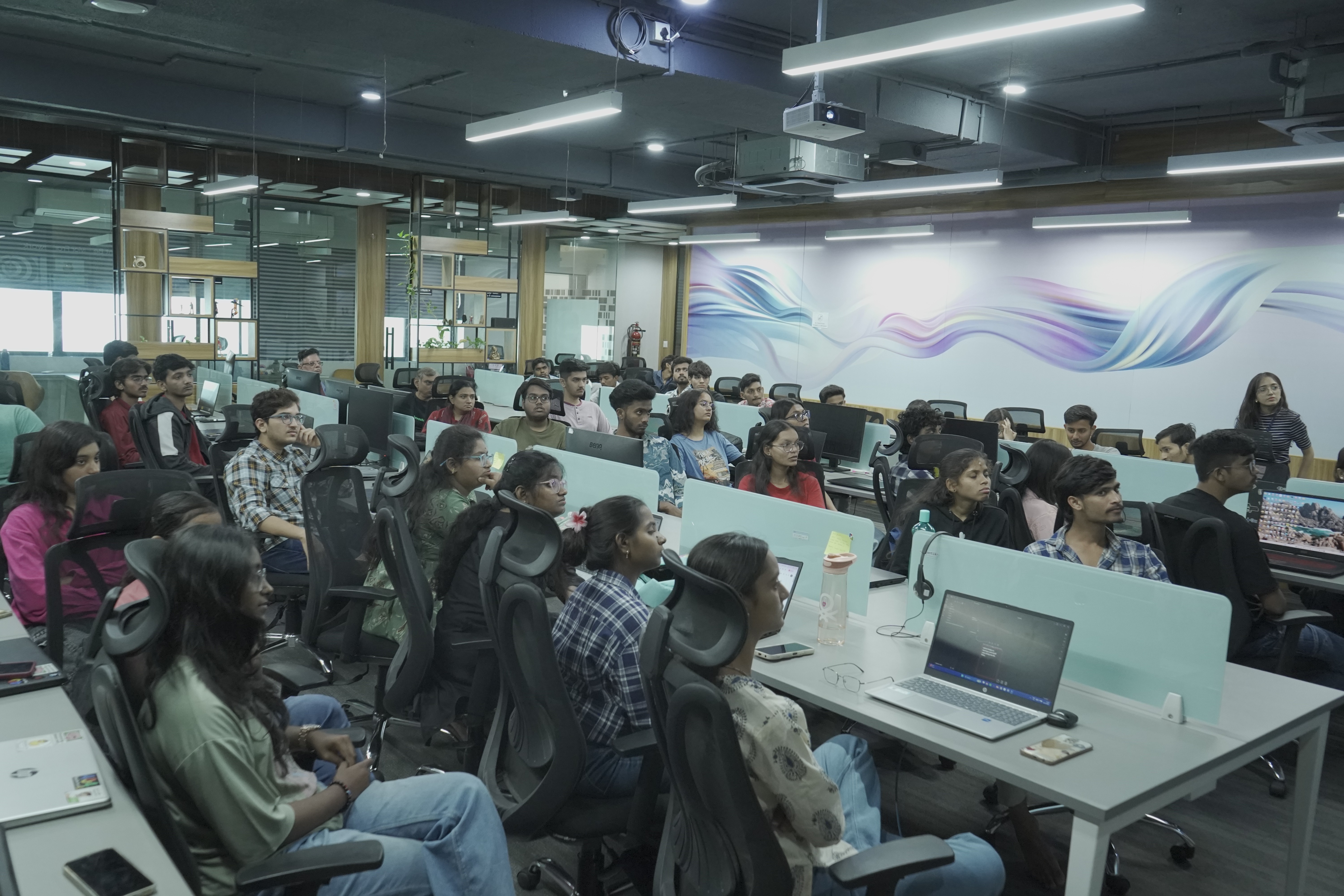 person discussing while standing in front of a large screen in front of people inside dim-lighted room