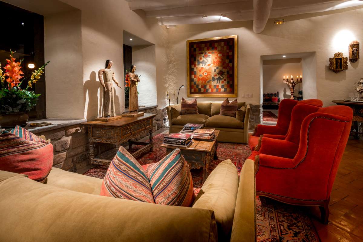 A cozy hotel lobby with red armchairs, a large painting, and a reception desk decorated with flowers and pillows.