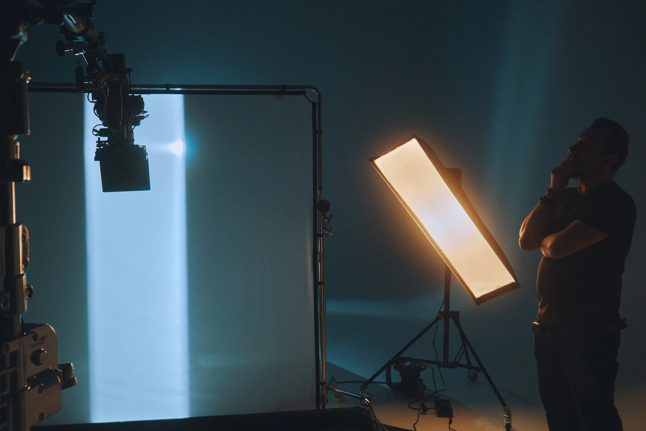 A man standing next to a camera and lighting equipment