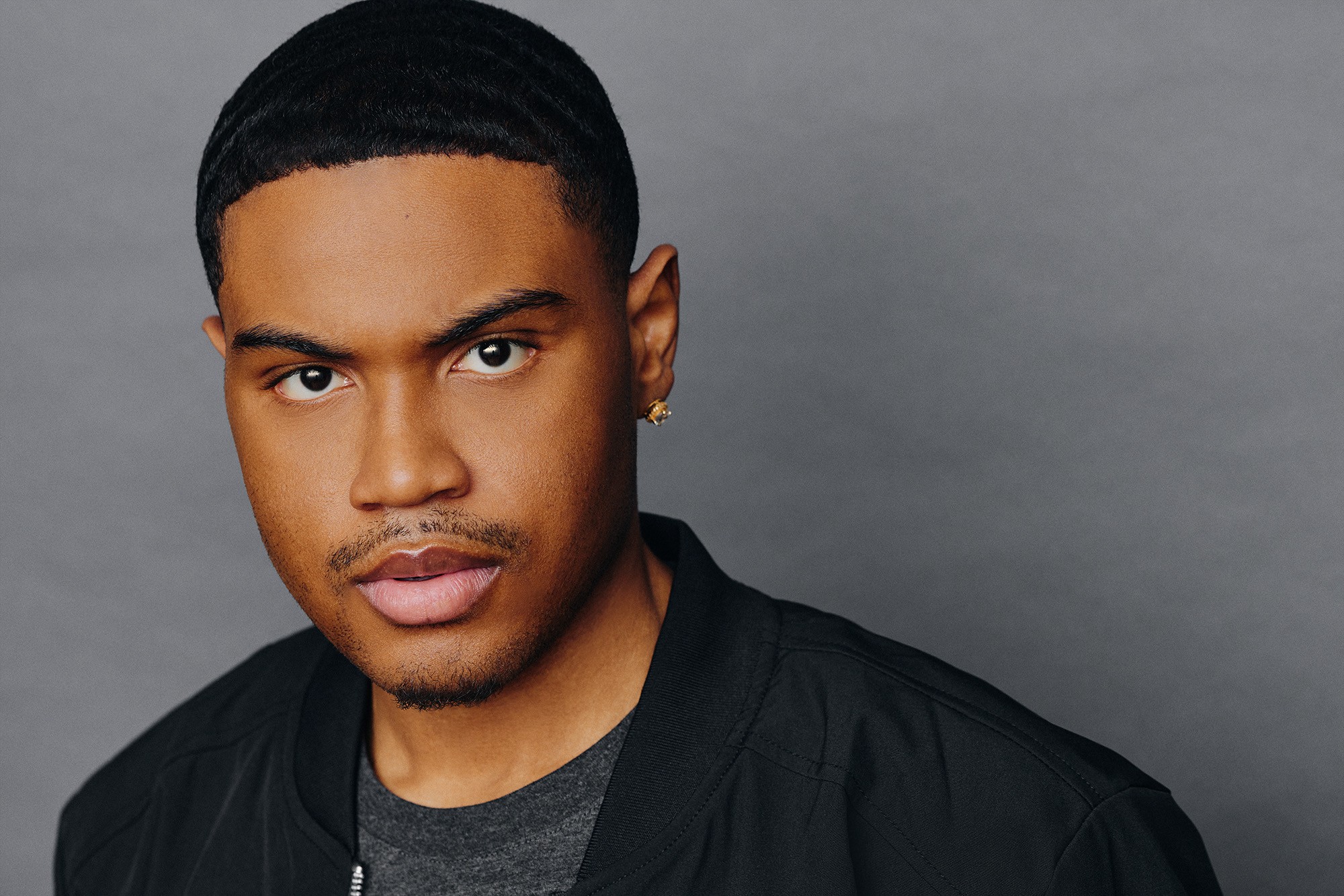 Latrel Crawford’s original theatrical headshot in a black jacket against a gray background