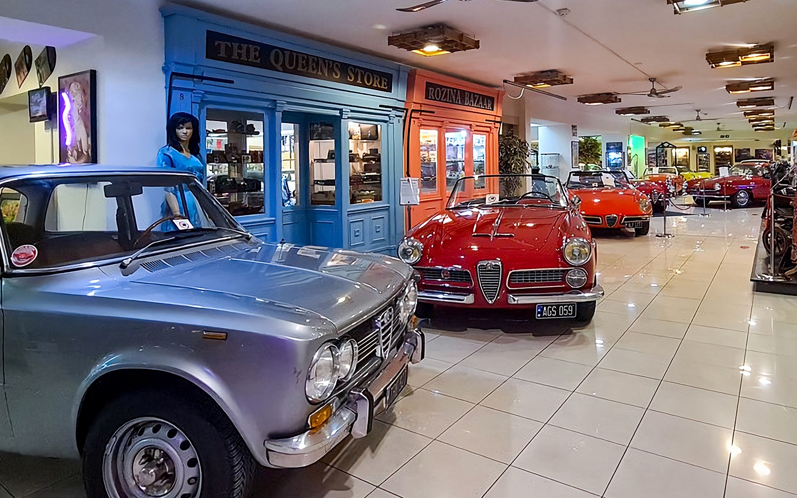 Classic cars and motorcycles displayed in a vintage-themed showroom.