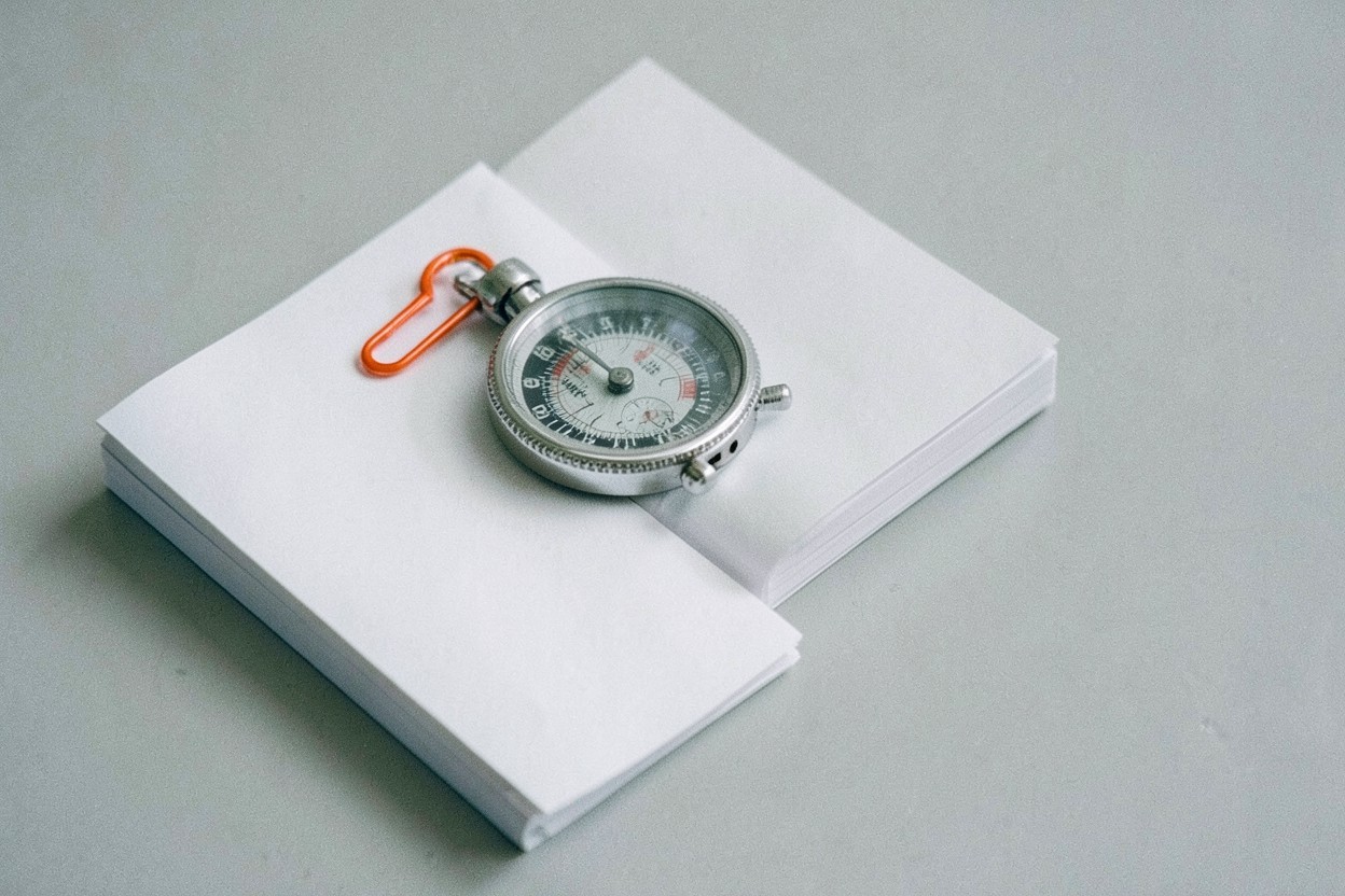 Stopwatch with an orange clip resting on a stack of paper