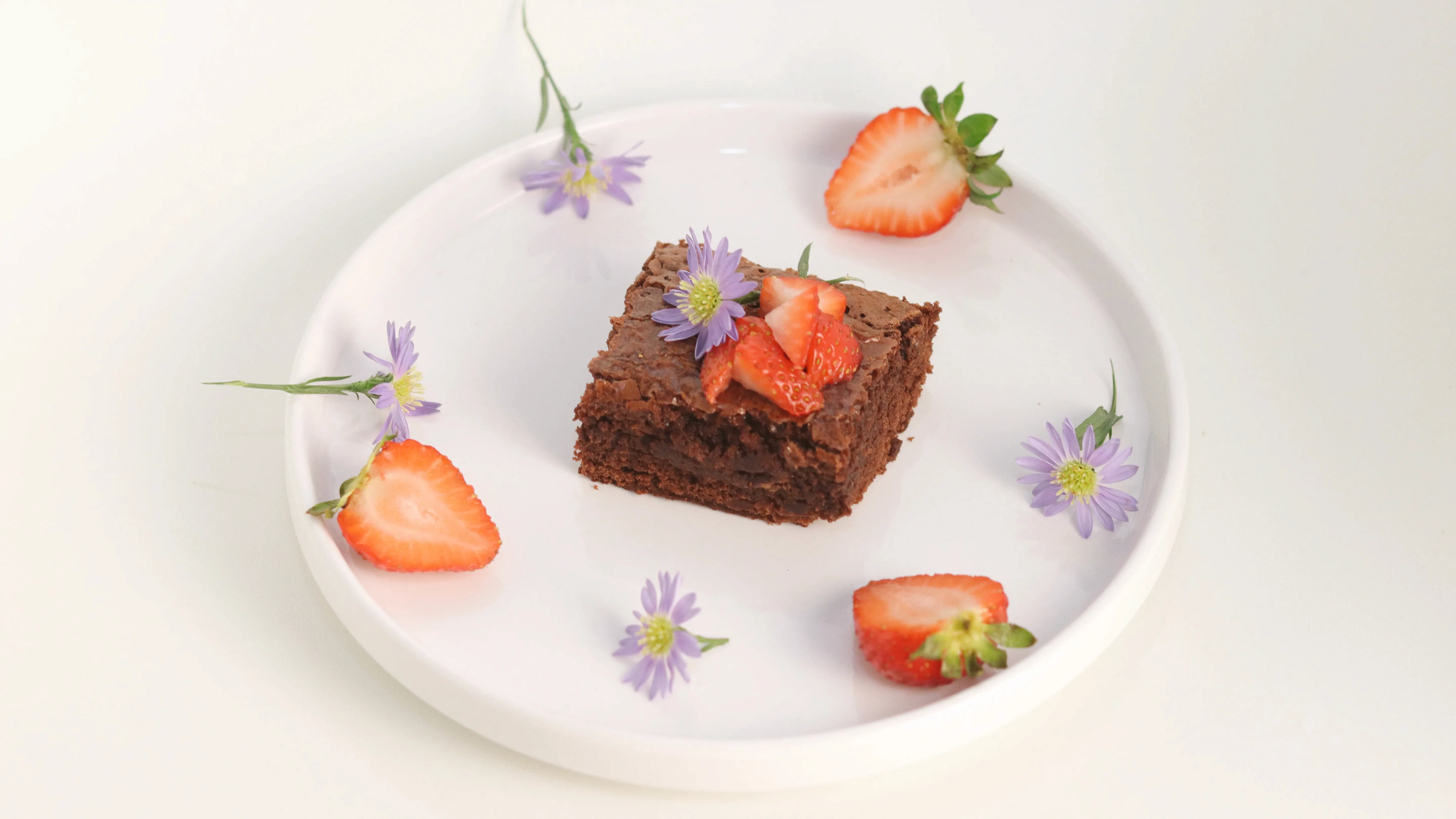 Brownie de chocolate con fresas decorado con flores comestibles