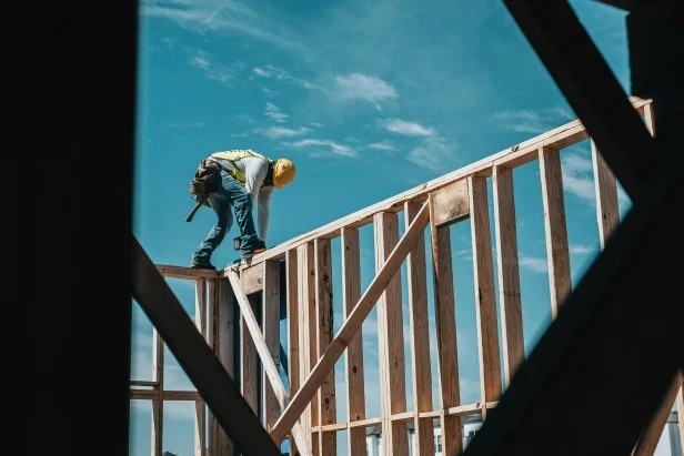 Man on a wooden frame constructing a house