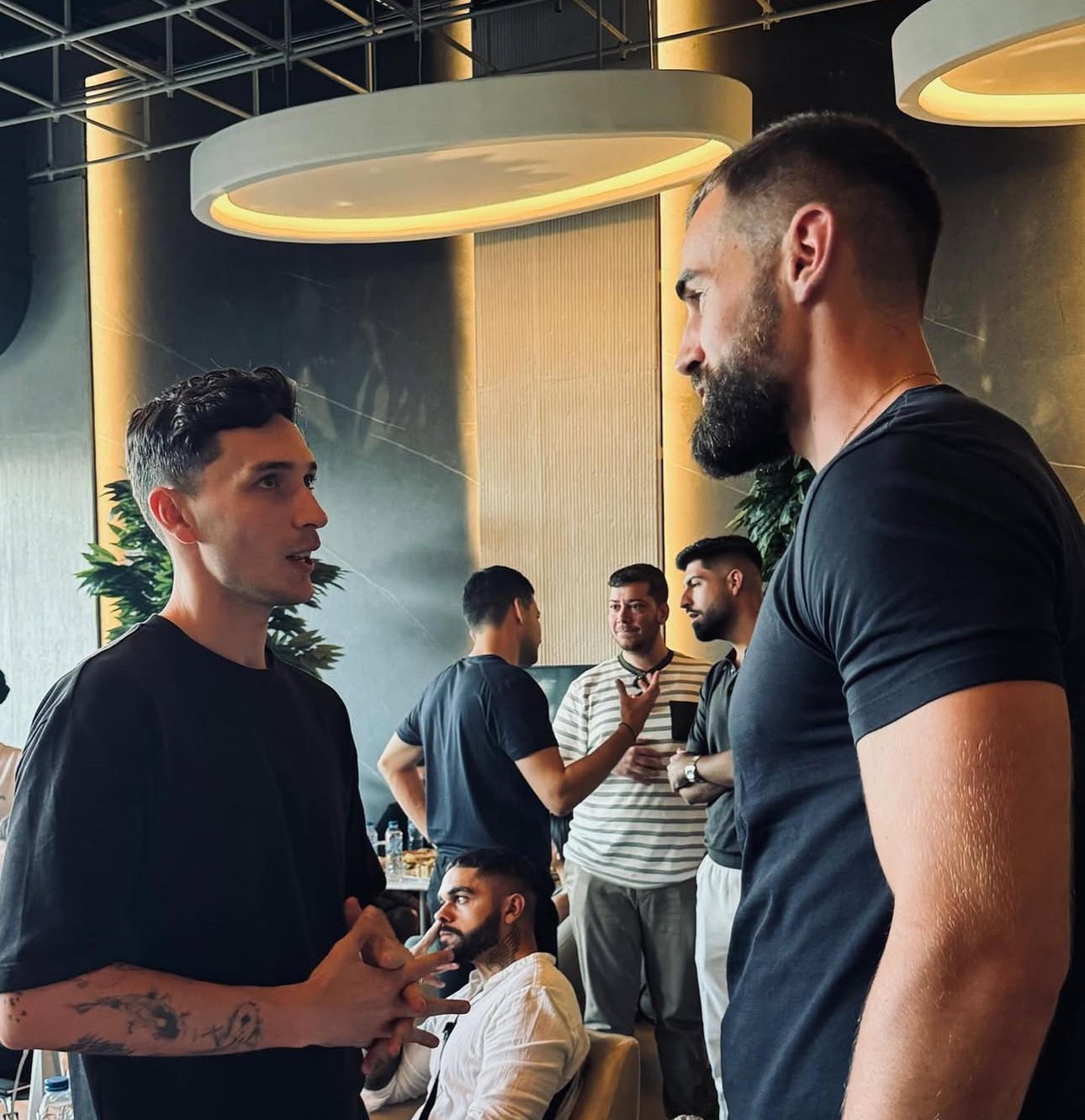 Professional headshot of a business advisor in a white shirt, smiling confidently against a warm neutral background.