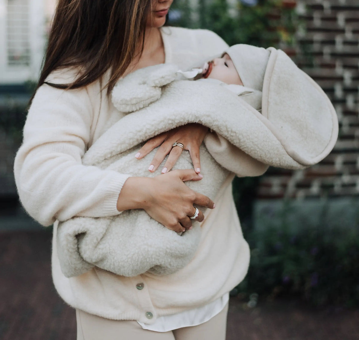 Baby in een wollen wikkeldeken in de armen van een ouder