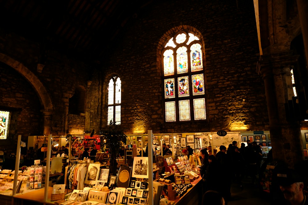 Makers' stalls inside an old stone hall with a stained-glass window
