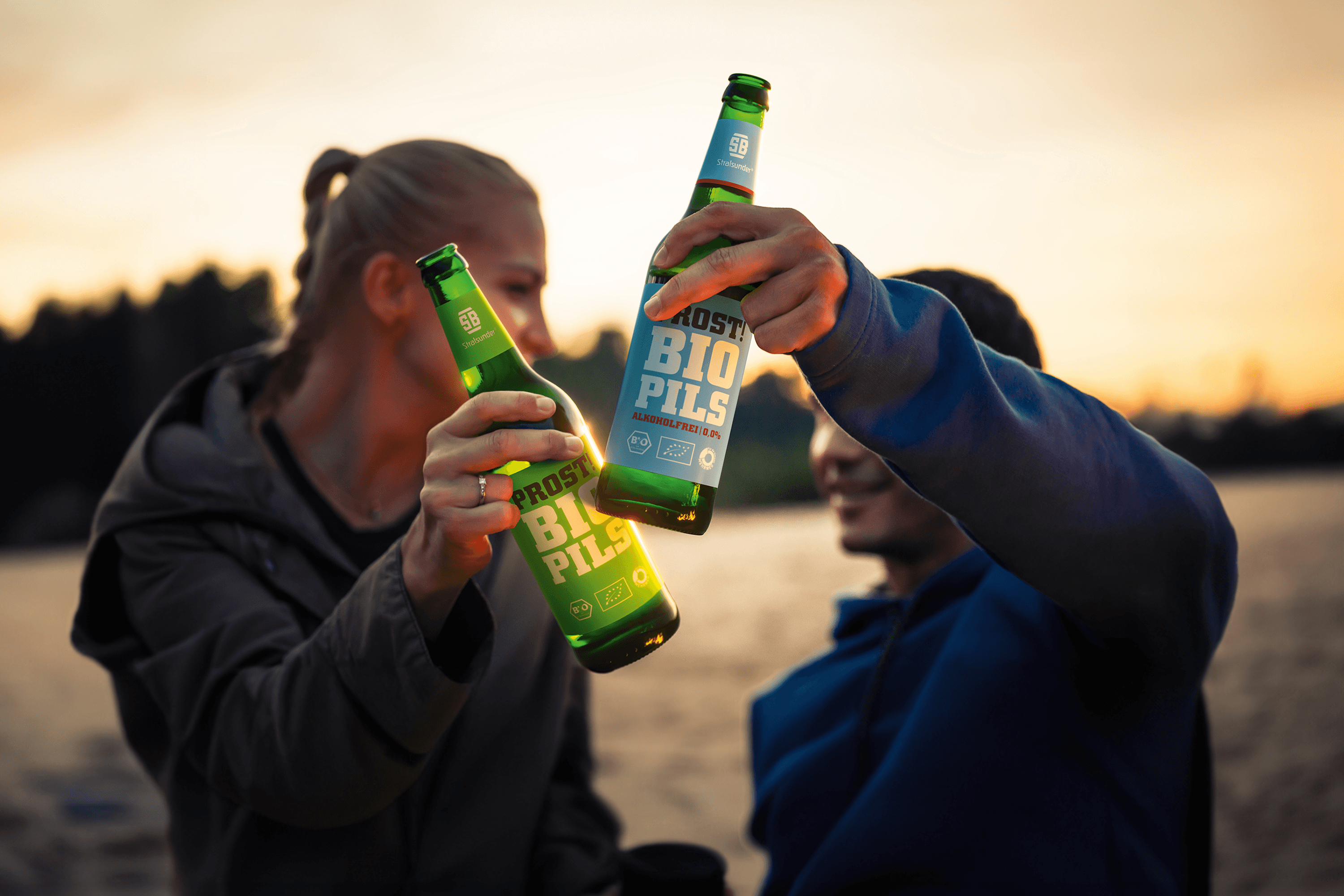 Two people toasting with bottles of Stralsunder Bio Pils