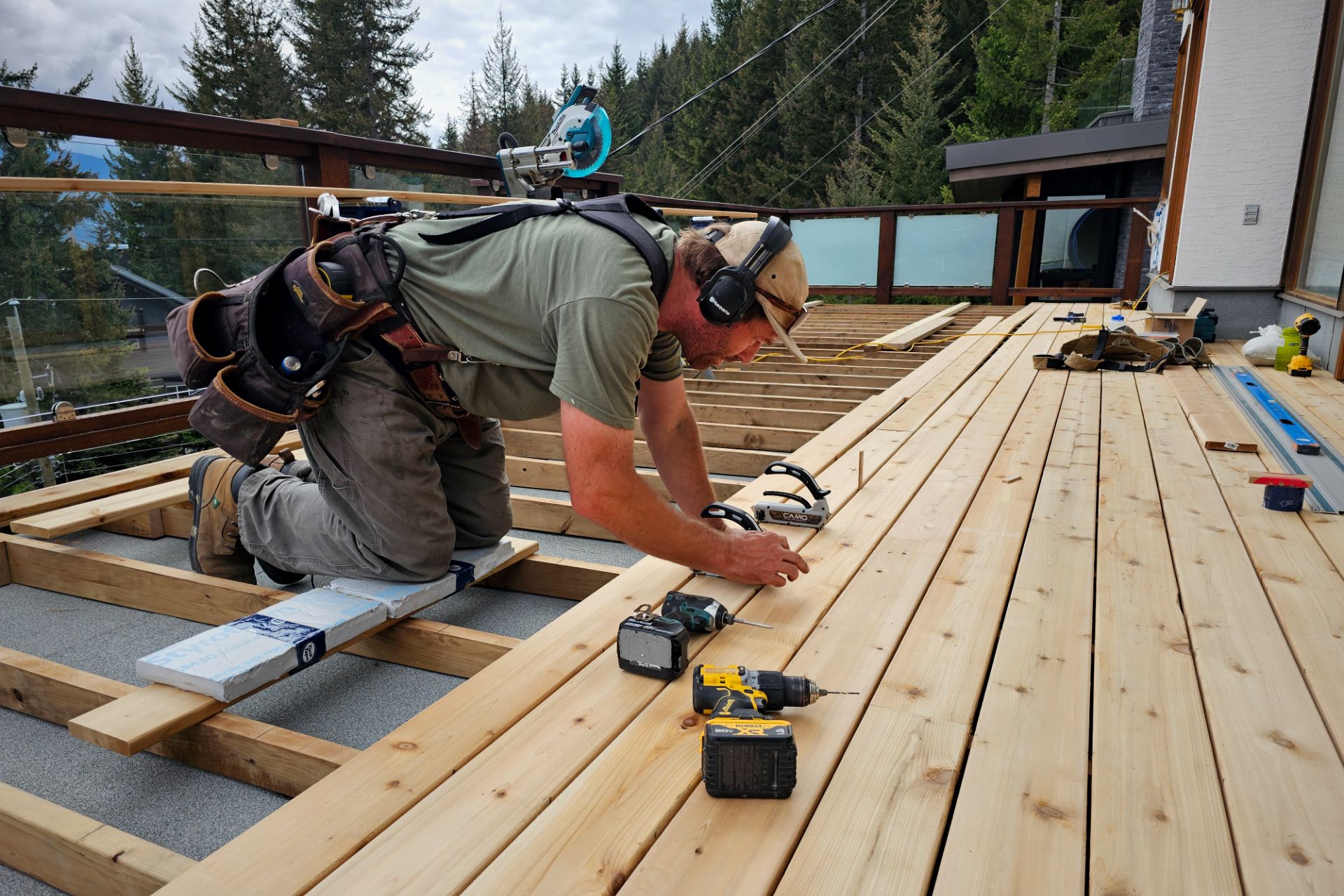 Golden Spruce carpenter installing cedar decking on a Whistler home with mountain views in the background.