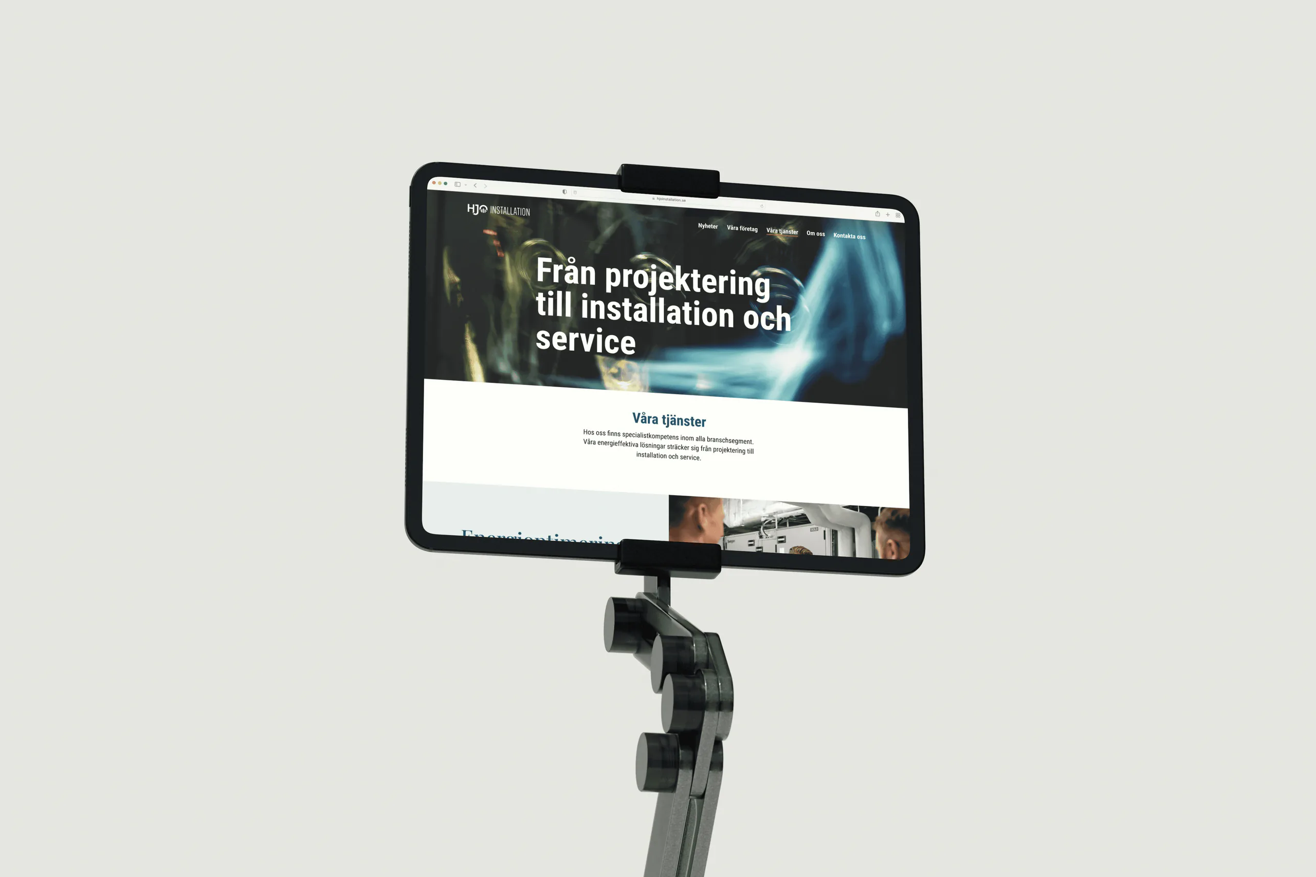 En surfplatta i ett stativ visar webbplatsen med rubriken Från projektering till installation och service