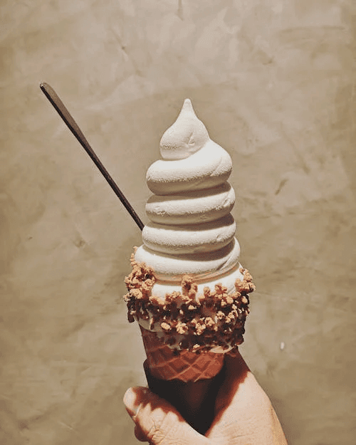 A hand holding a toffee ice cream cone