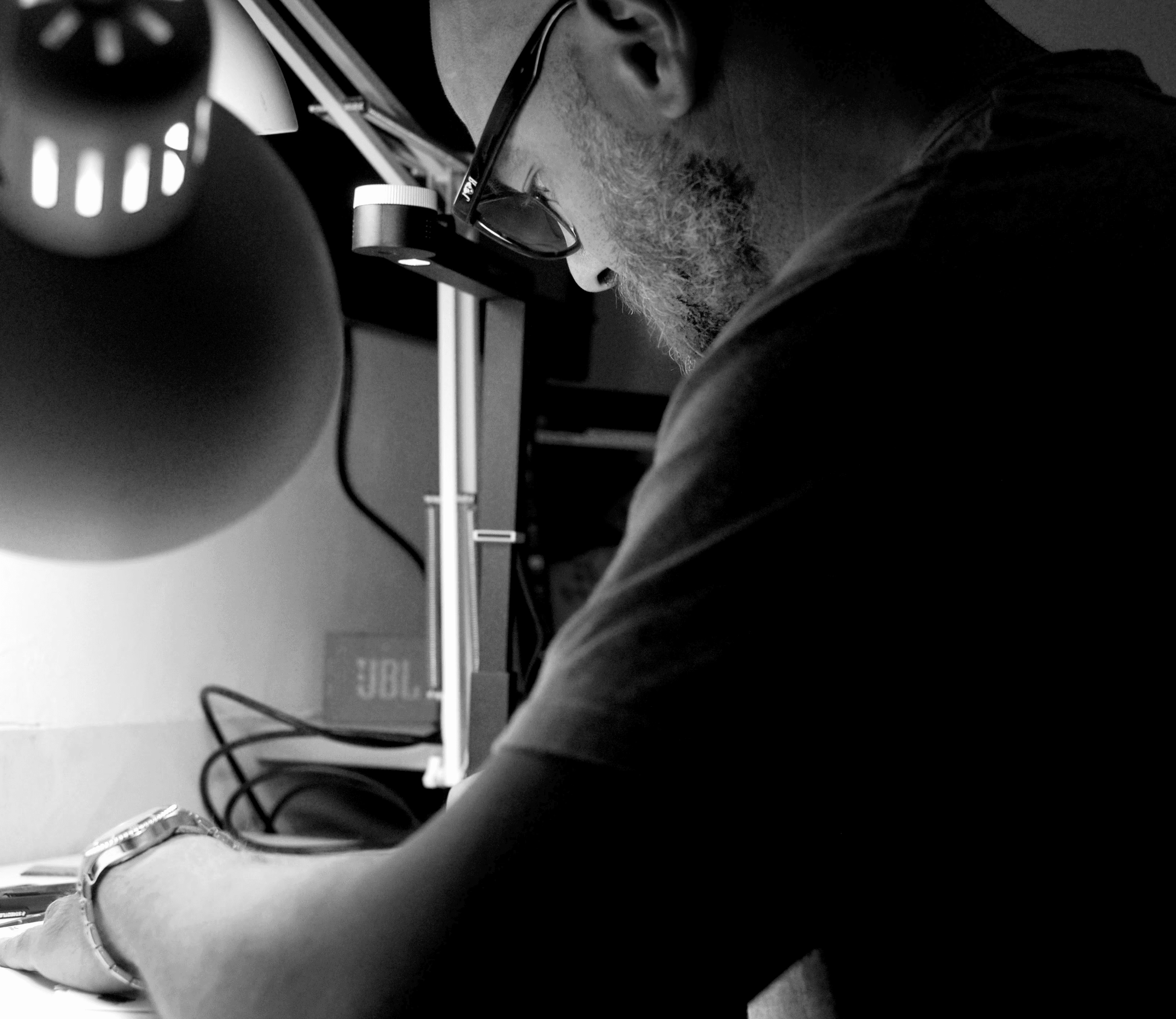 A thoughtful young person with dark hair gazes to the side, captured in soft black and white lighting.