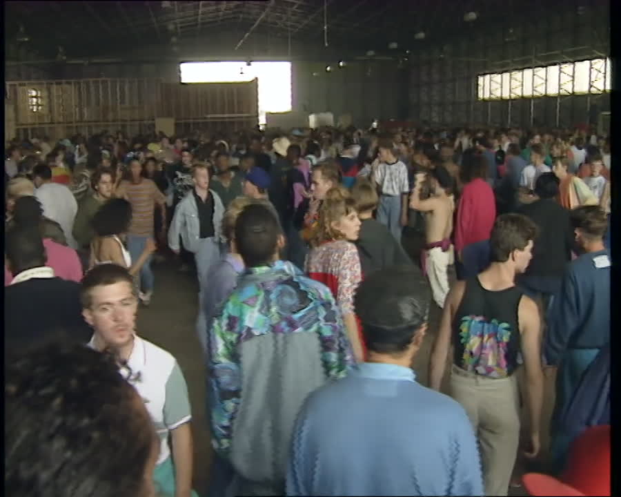 Crowd dancing inside warehouse at early 1990s illegal rave