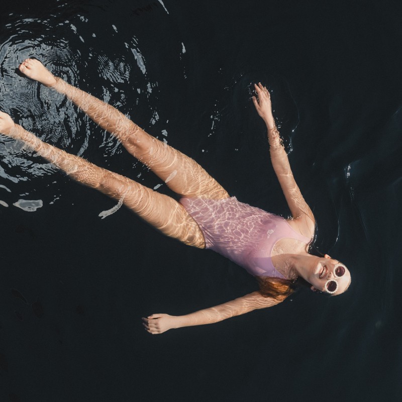 Top-down photo of a young woman wearing a bathing suit and floating in the ocean