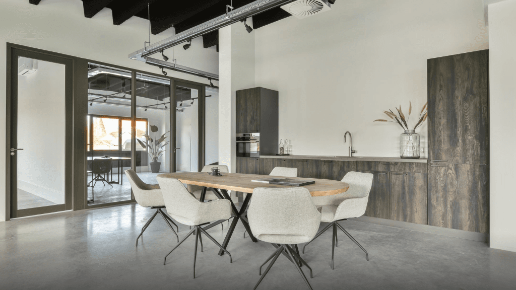Modern dining area with a wooden table, gray chairs, and a sleek kitchen in a minimalist, well-lit space