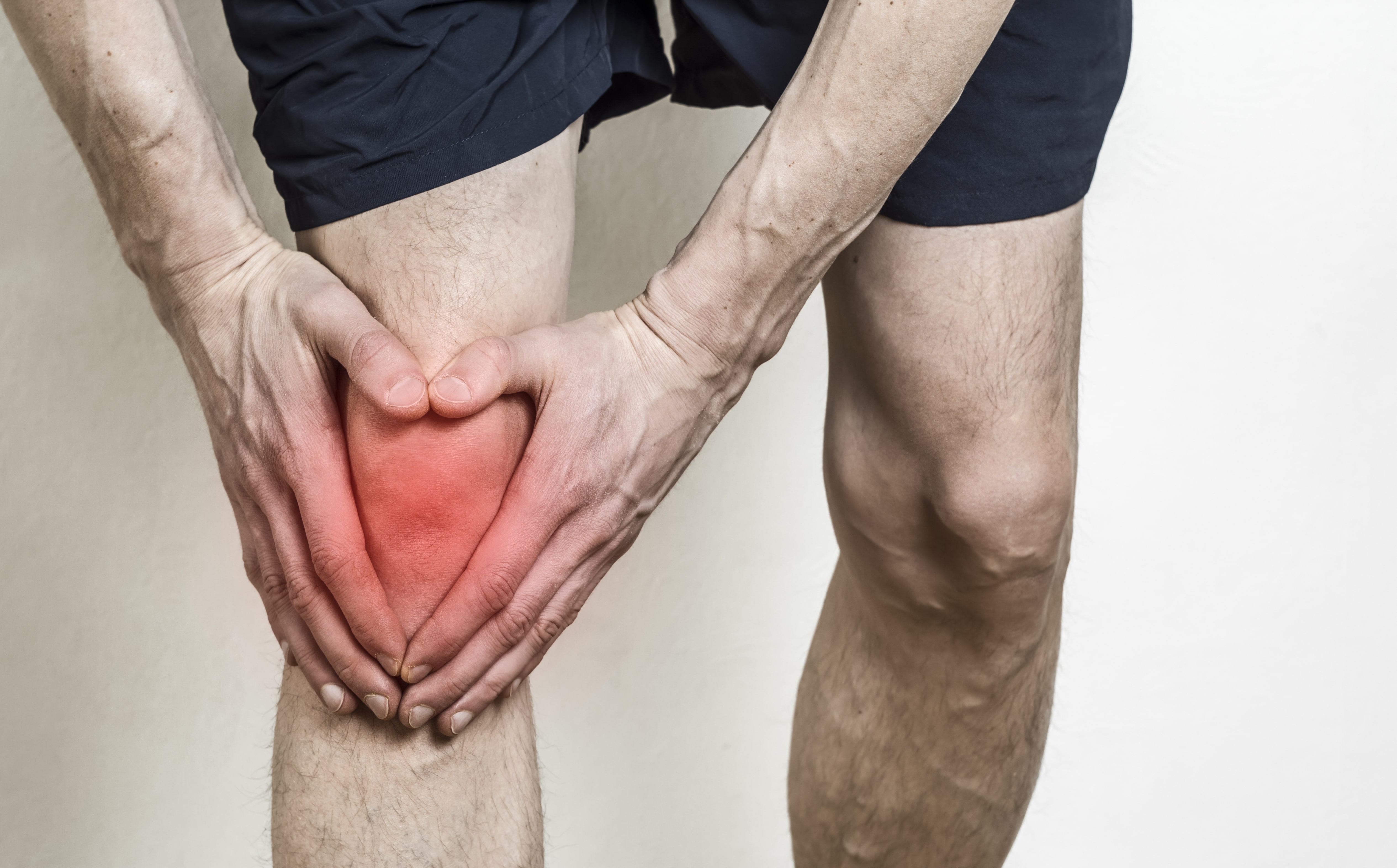 Männliche Person die sich das Knie vor Schmerzen hält