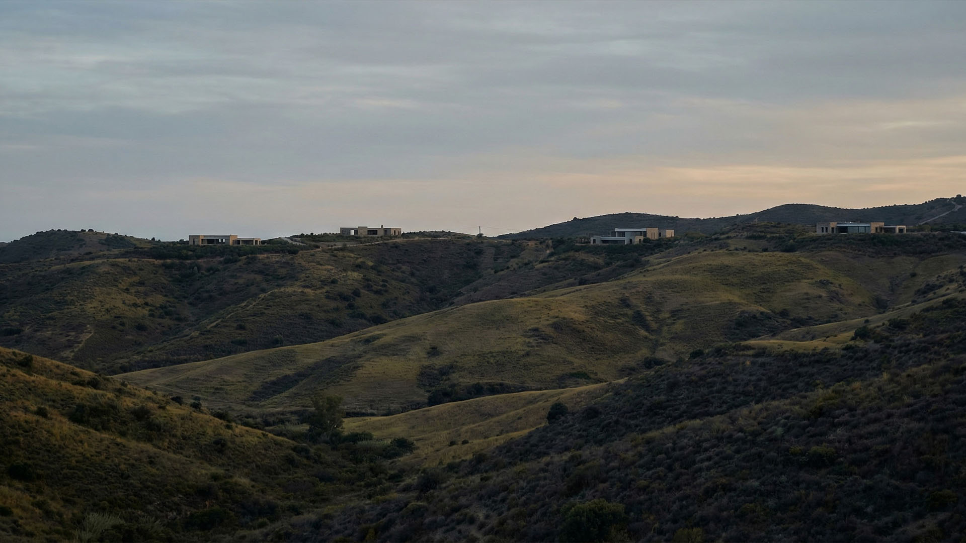 Scenic hillside landscape in Marbella with luxury villas overlooking natural terrain and sunset sky
