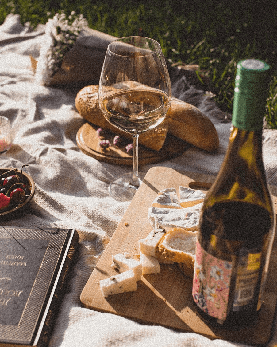 Fotografía de picnic con vino blanco La Justina, pan y quesos artesanales, evocando momentos de disfrute y elegancia natural.