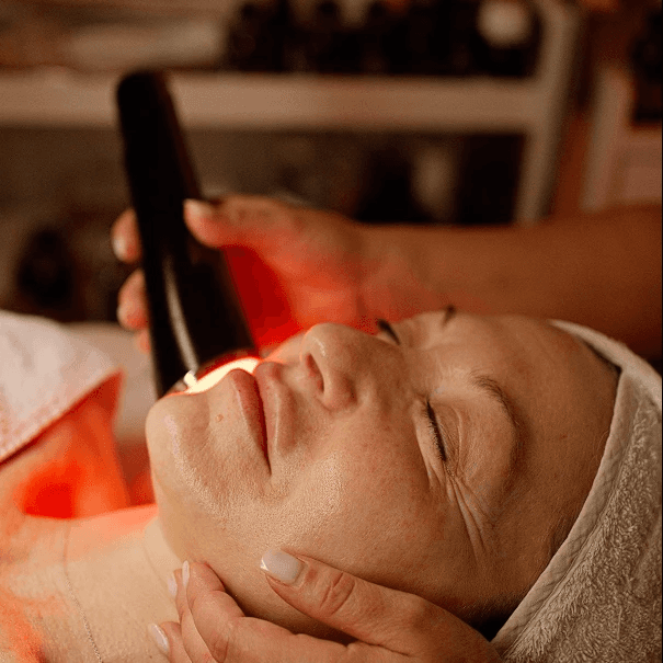 Smiling woman holding a rose quartz face roller, using it for a self-massage on her face