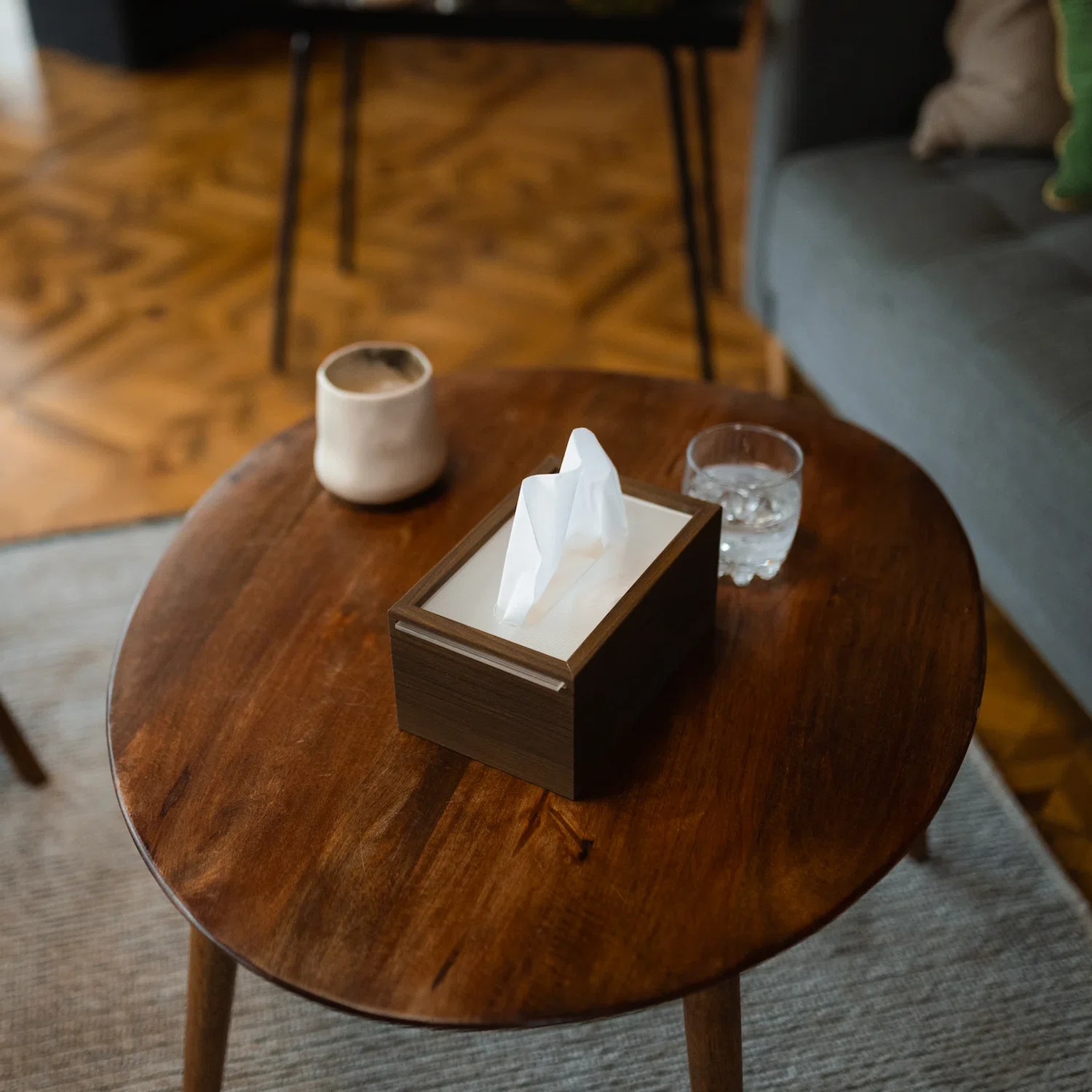 Close-up of a wooden table in a cozy therapy office with tissues, water, and a mug prepared for an in-person therapy session in New York City.