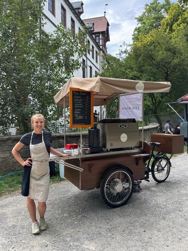 Sympathische Barista von 'Bens Beans' an ihrem mobilen Kaffee-Fahrrad mit Kaffeemaschine, bereit für euren Hochzeits-Ausschank.