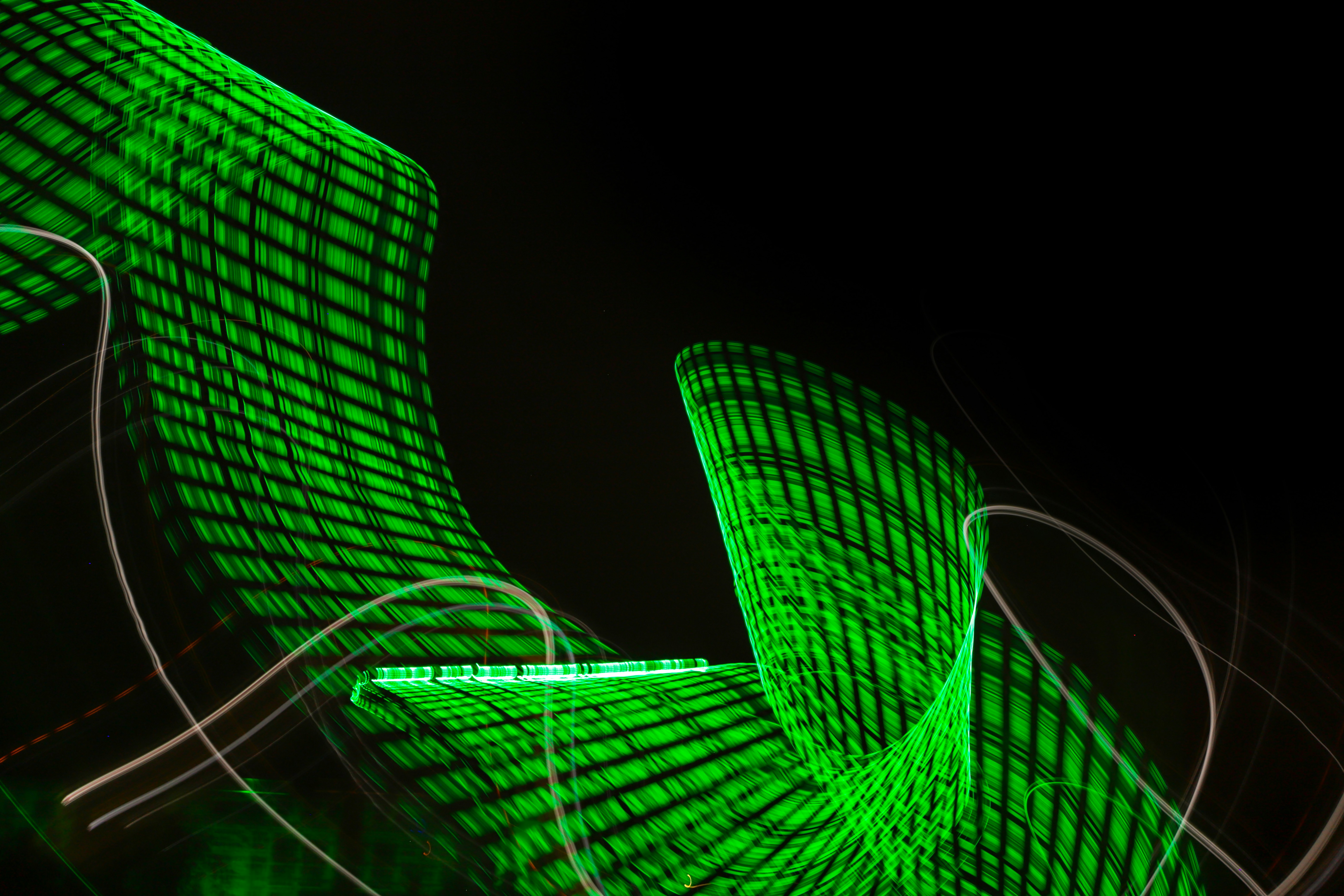 Abstract image of green light trails forming a grid pattern against a black background.
