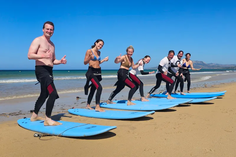 Clases de surf para principiantes en la playa con un grupo de estudiantes en Explora Watersports Tarifa