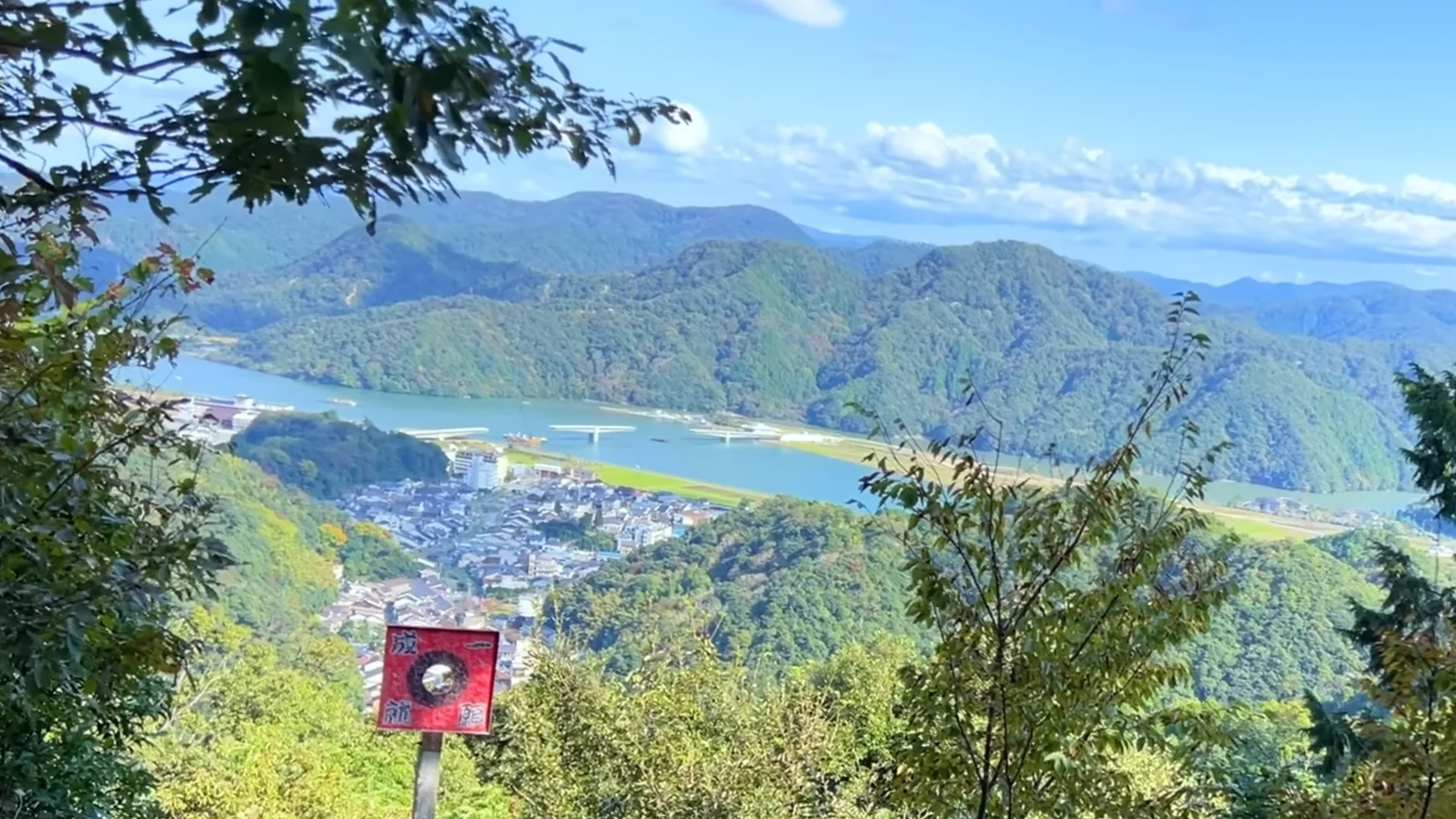 Autumn view from the Kinosaki ropeway summit over forested ridges to the river mouth.