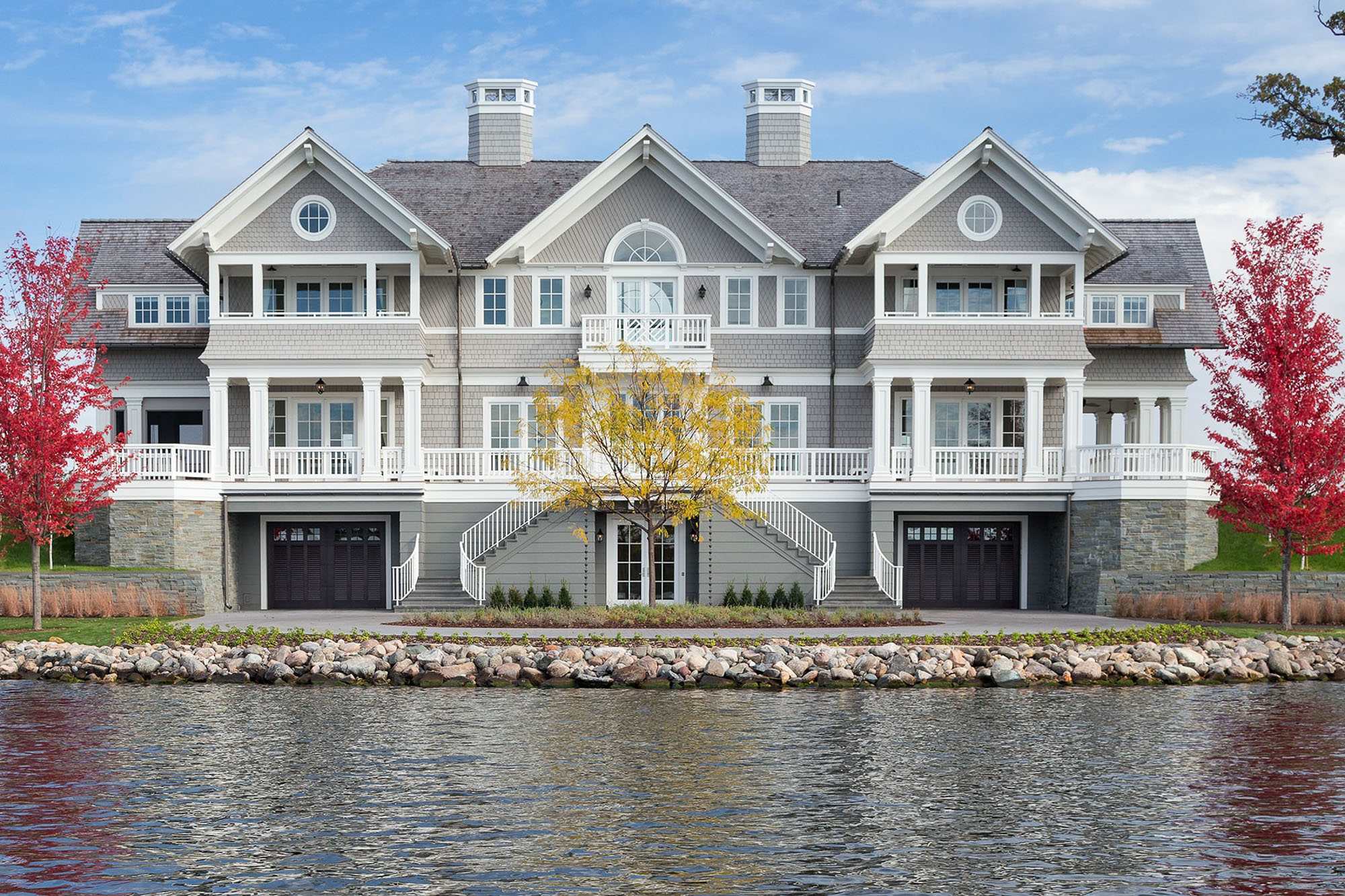 Grey shingle-style waterfront estate with white trim and multiple porches. Owner's Representation by Curated by Streeter.