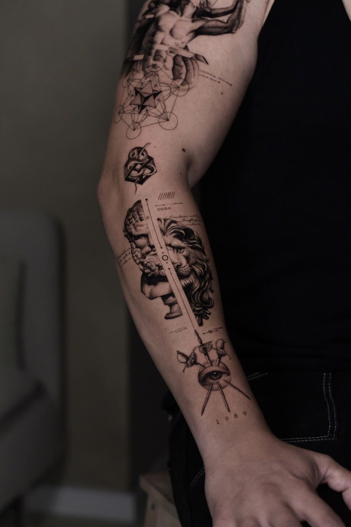 A realistic forearm tattoo featuring a lion and hercules sculpture statue , combined with handwritten script and geometric , blending Greek and Renaissance aesthetics.