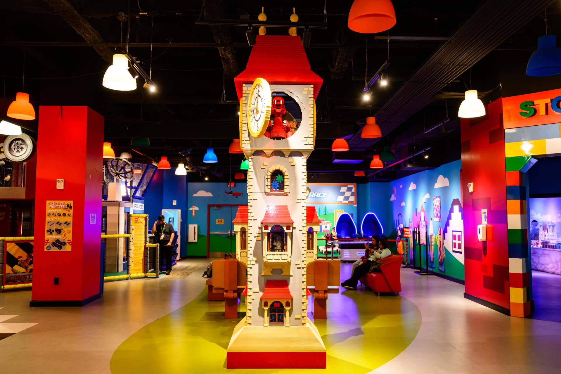 LEGO clock tower model at the center of the LEGOLAND Discovery Center play area, surrounded by colorful brick-themed exhibits