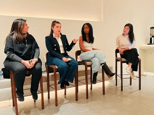 Four women speaking on tall wooden chairs