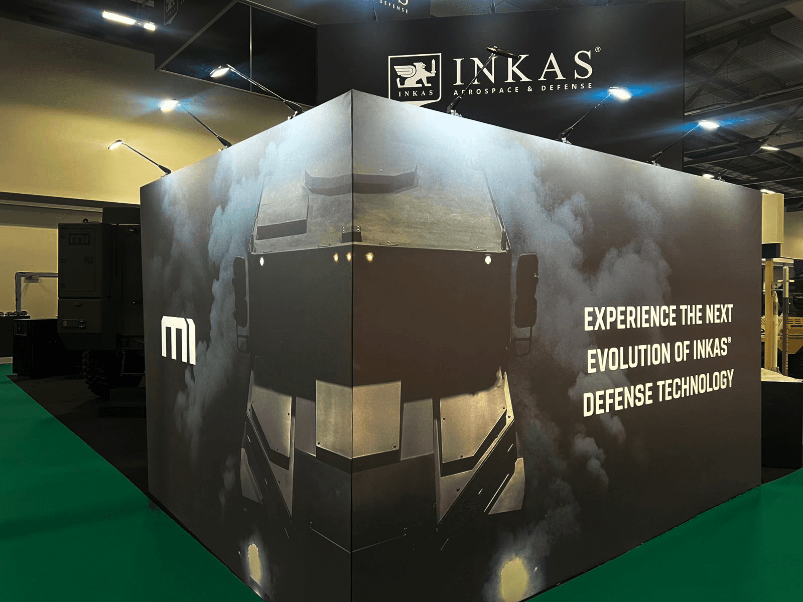Stand INKAS Armored Farnborough 2026 conçu par Expace – espace privatif fermé avec signature Defense Technology et habillage graphique sombre salon défense international