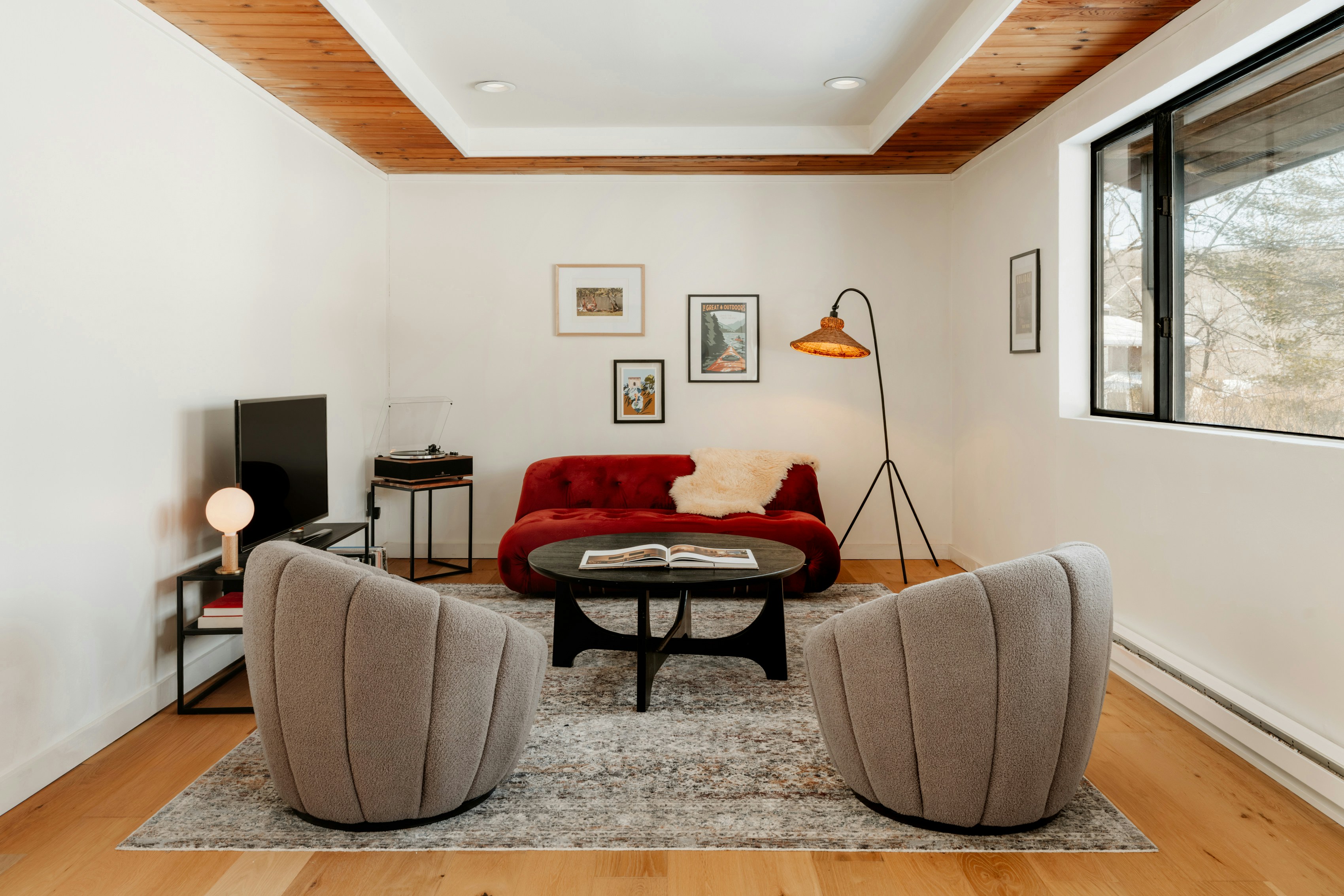 Modern living room with red sofa and grey chairs.