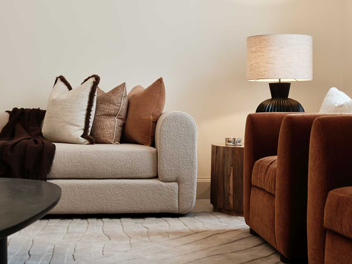 Modern living room seating styled by Doll & Co. South Bank Architects featuring a plush bouclé sofa, terracotta armchair, and table lamp.