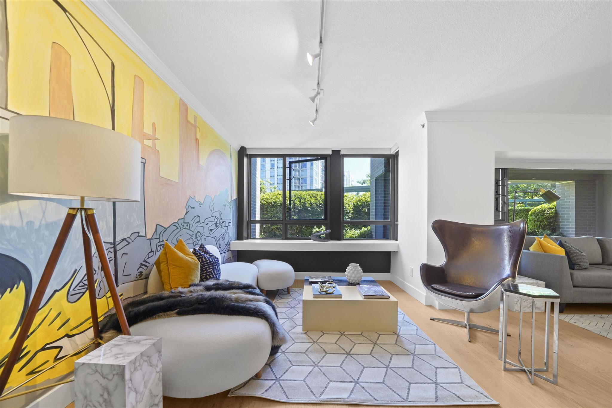 Modern living room with large windows, cozy seating, and vibrant yellow accents, creating a bright and inviting space.