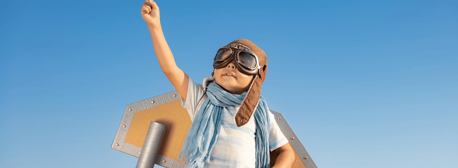 enfant avec un déguisement d'avion en carton qui pointe vers le ciel