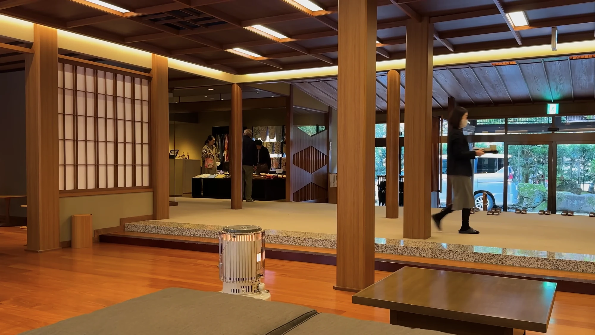 A timber-framed ryokan lobby in Kinosaki with tatami seating and a garden beyond the glass.