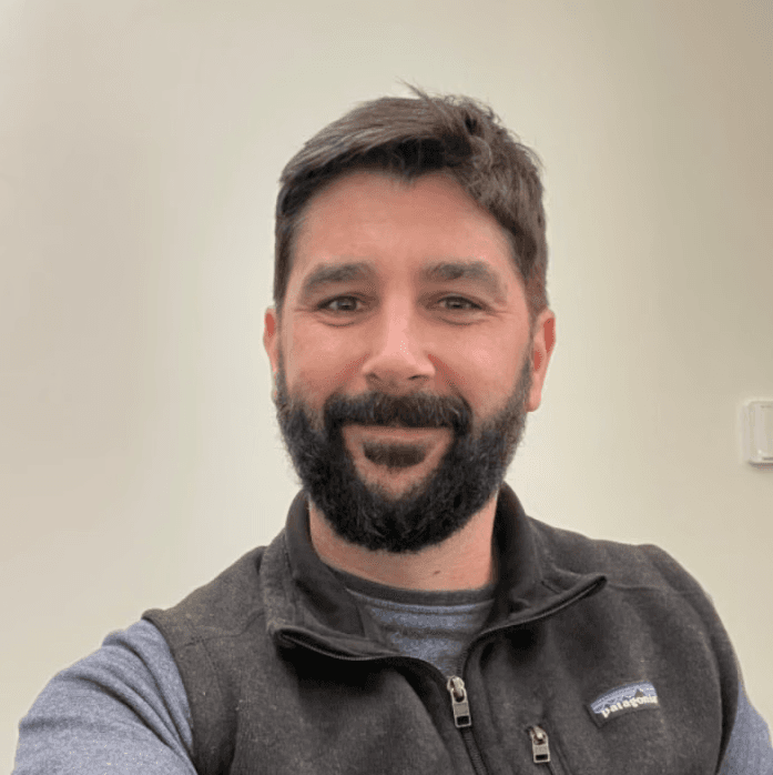 man with beard smiles into camera