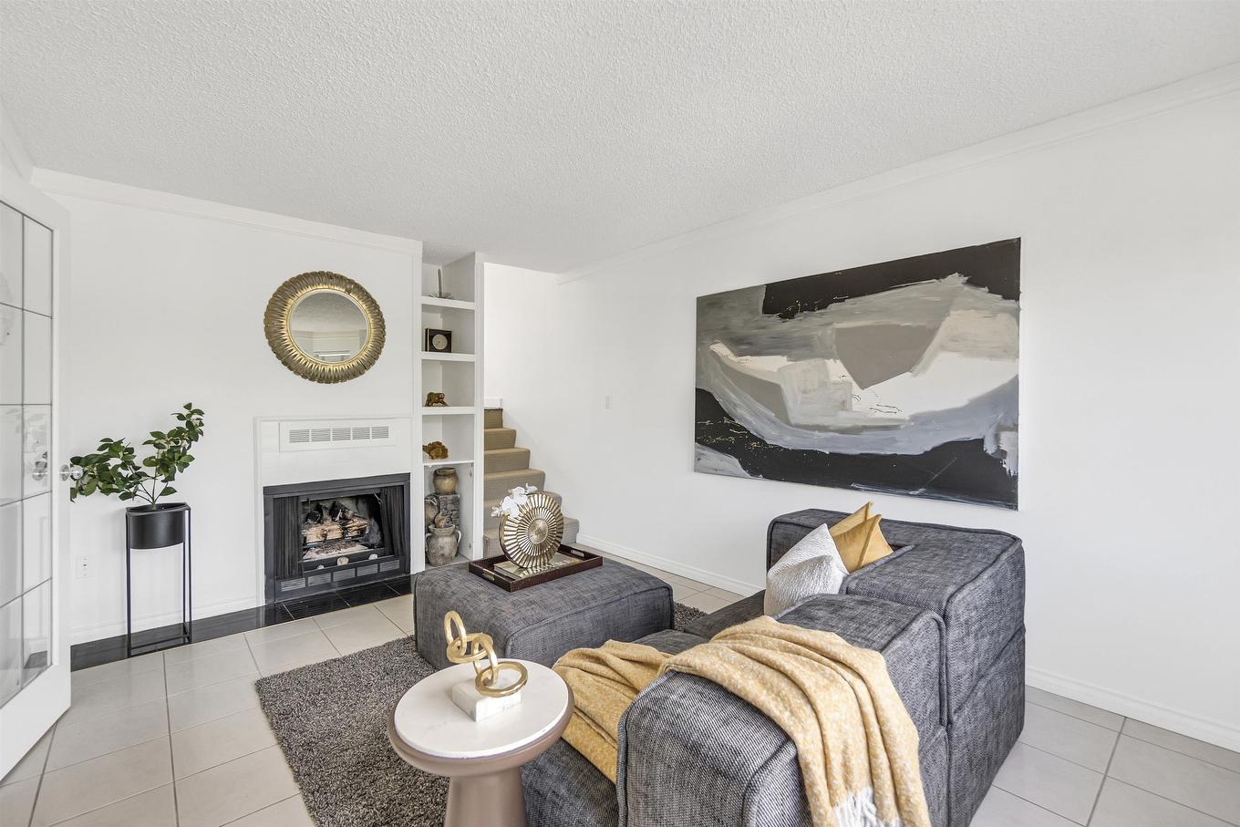 Modern living room with gray furniture, decorative throw, and a fireplace, featuring a large abstract painting.