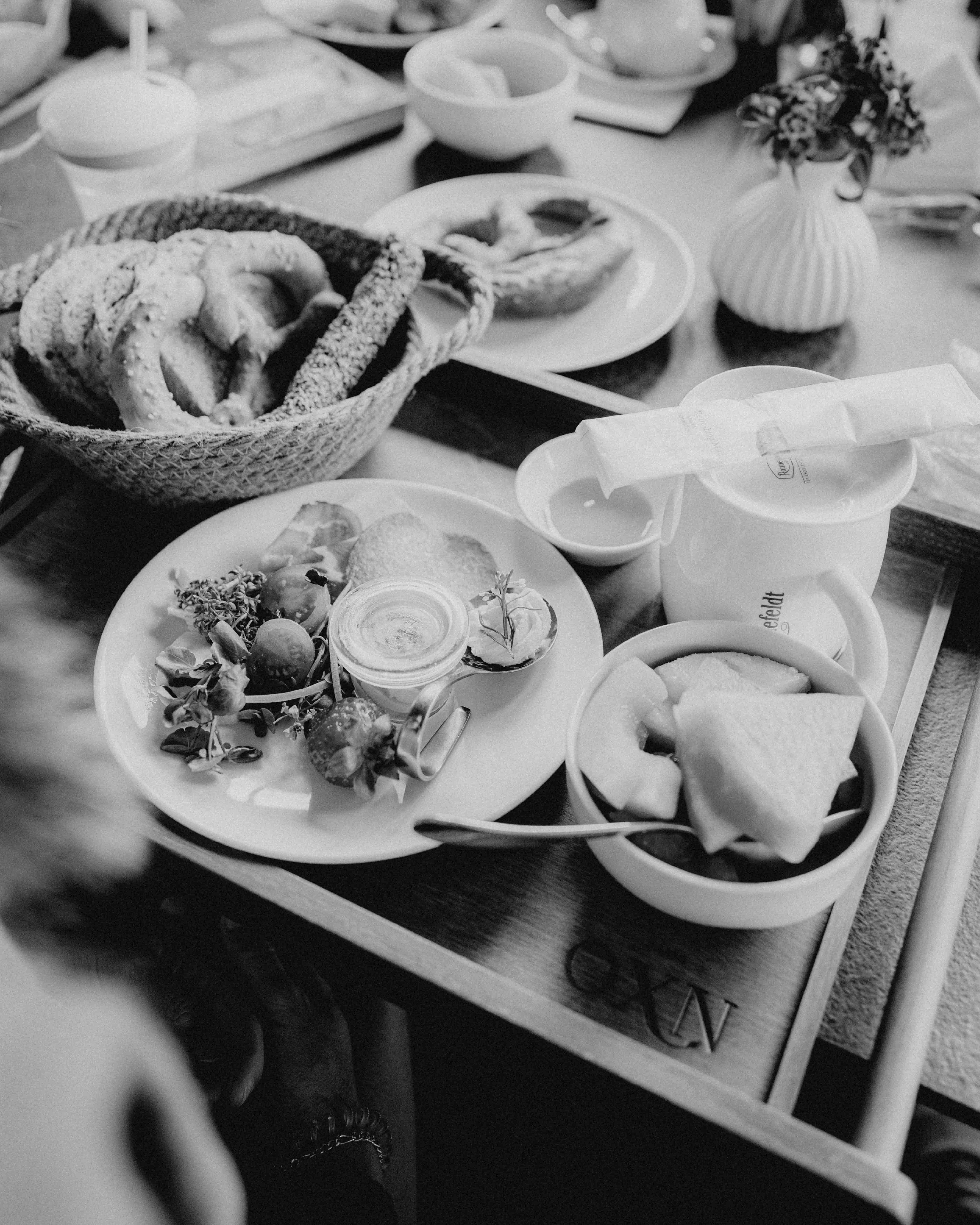 A close-up of a table laden with various bowls of food, showcasing a variety of dishes in black and white.