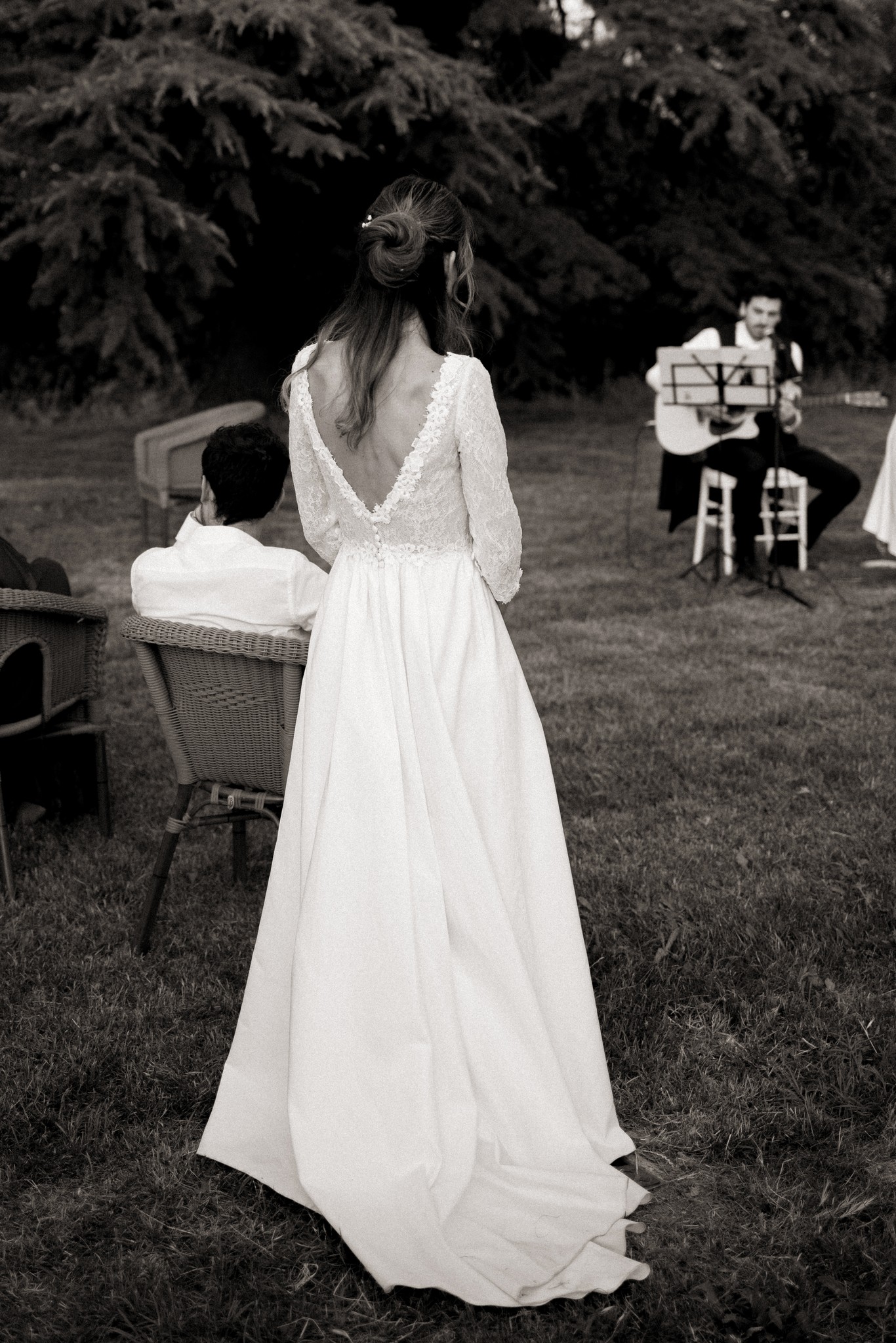 Sposa in abito bianco con schiena scoperta vista di spalle durante il ricevimento in giardino a Villa Peroni Riva