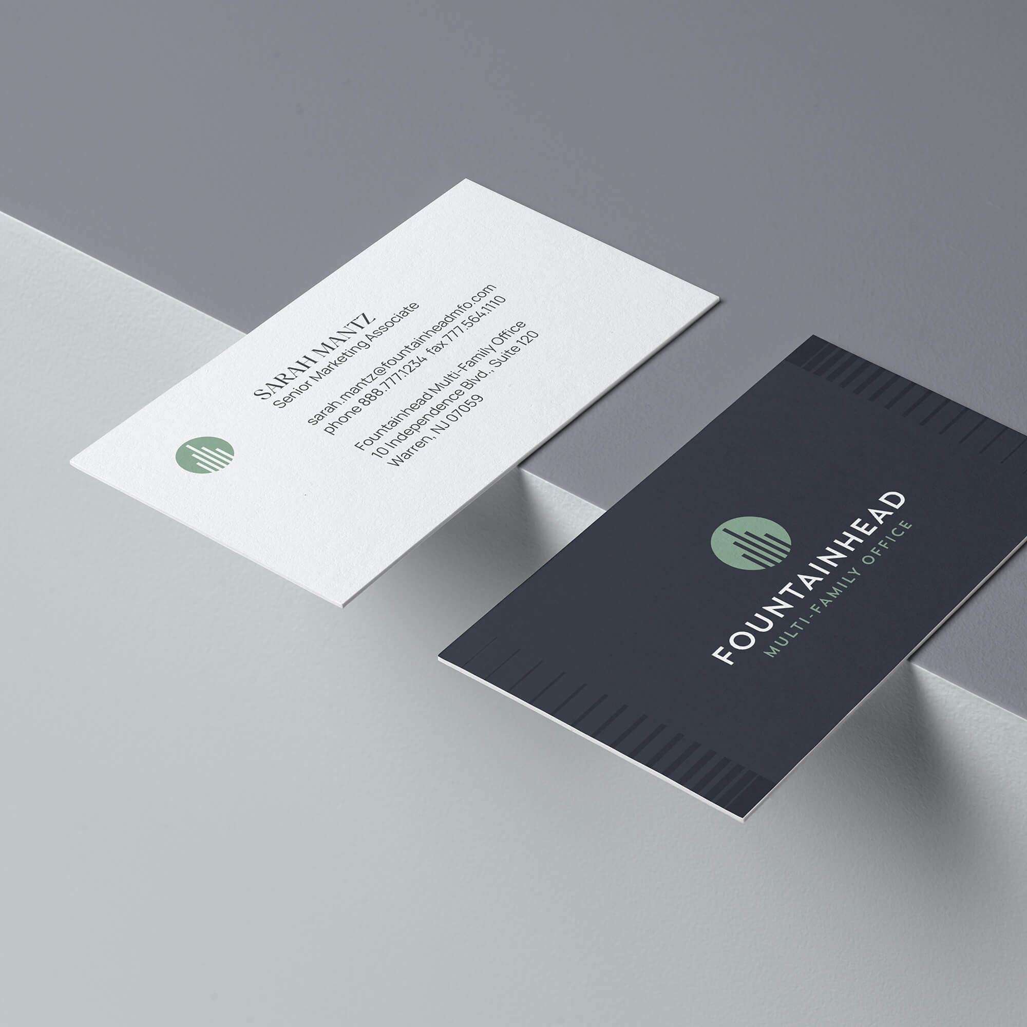 White and dark grey Fountainhead business cards on a grey background.