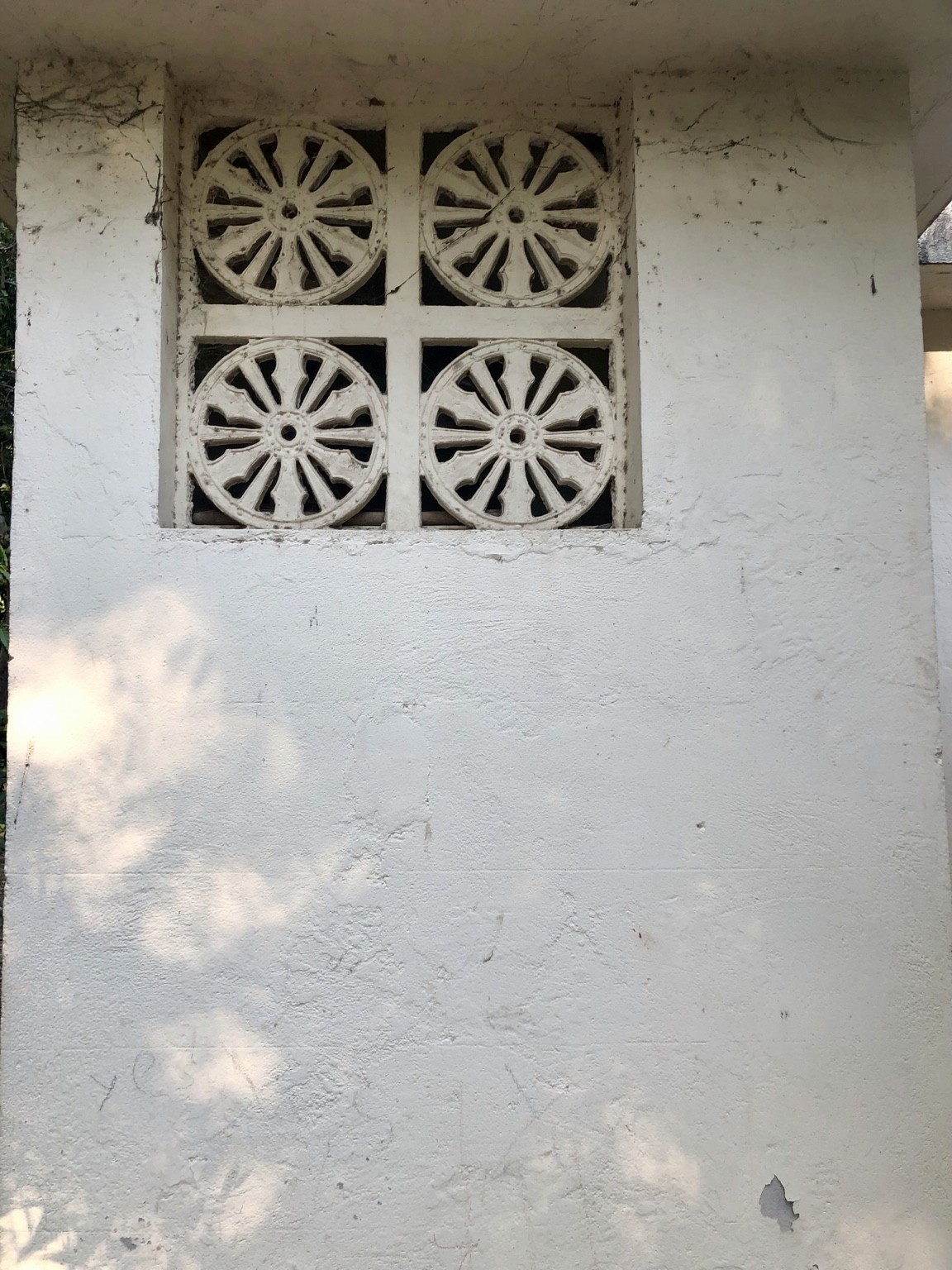 Four patterned circular vents set into a pale wall. Photograph by Pranjali Shah.