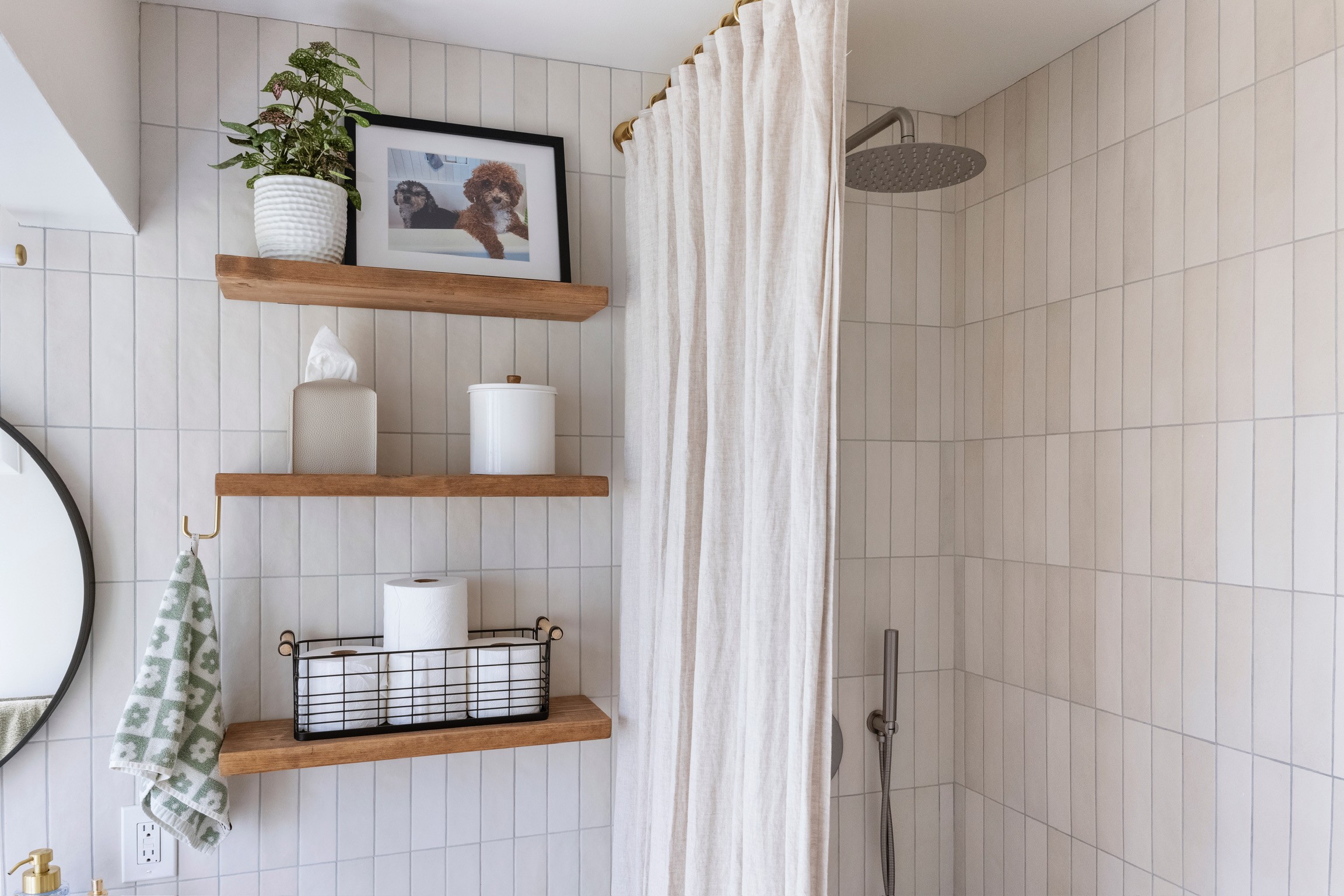 “Minimal shower remodel with white tile walls, rain shower head, and floating wood shelves”
