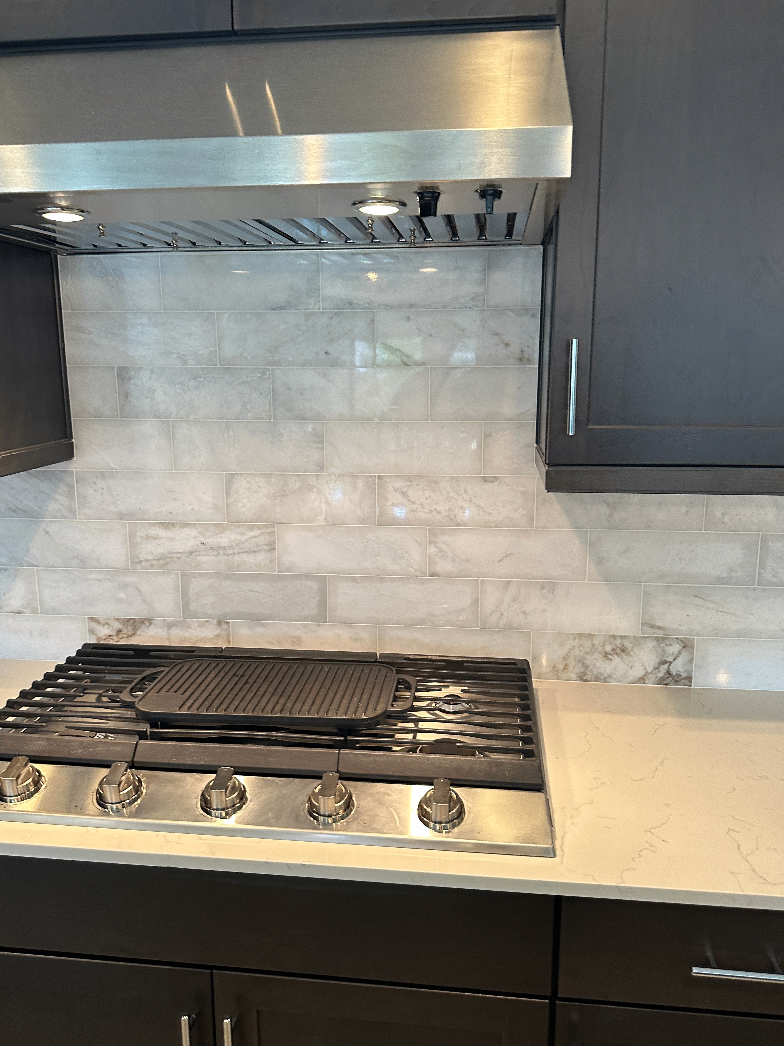 Contemporary kitchen with dark cabinets, a gas stovetop, and a white subway tile backsplash.